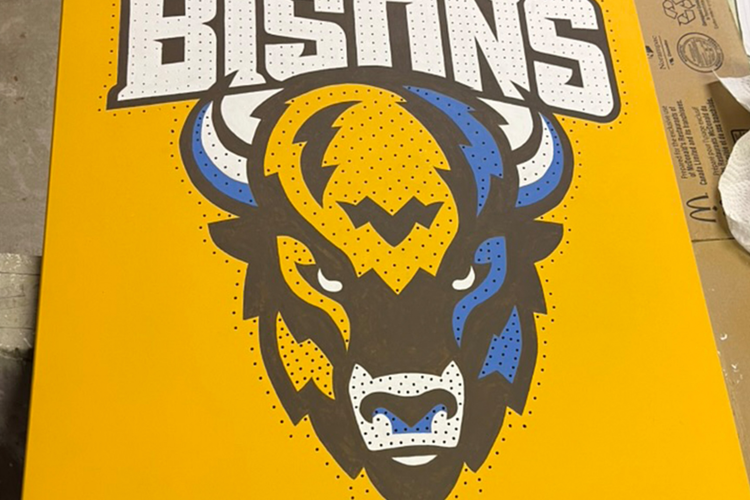 A close up of the Bison Sports logo on a MDF board with thousands of holes ready for screws.