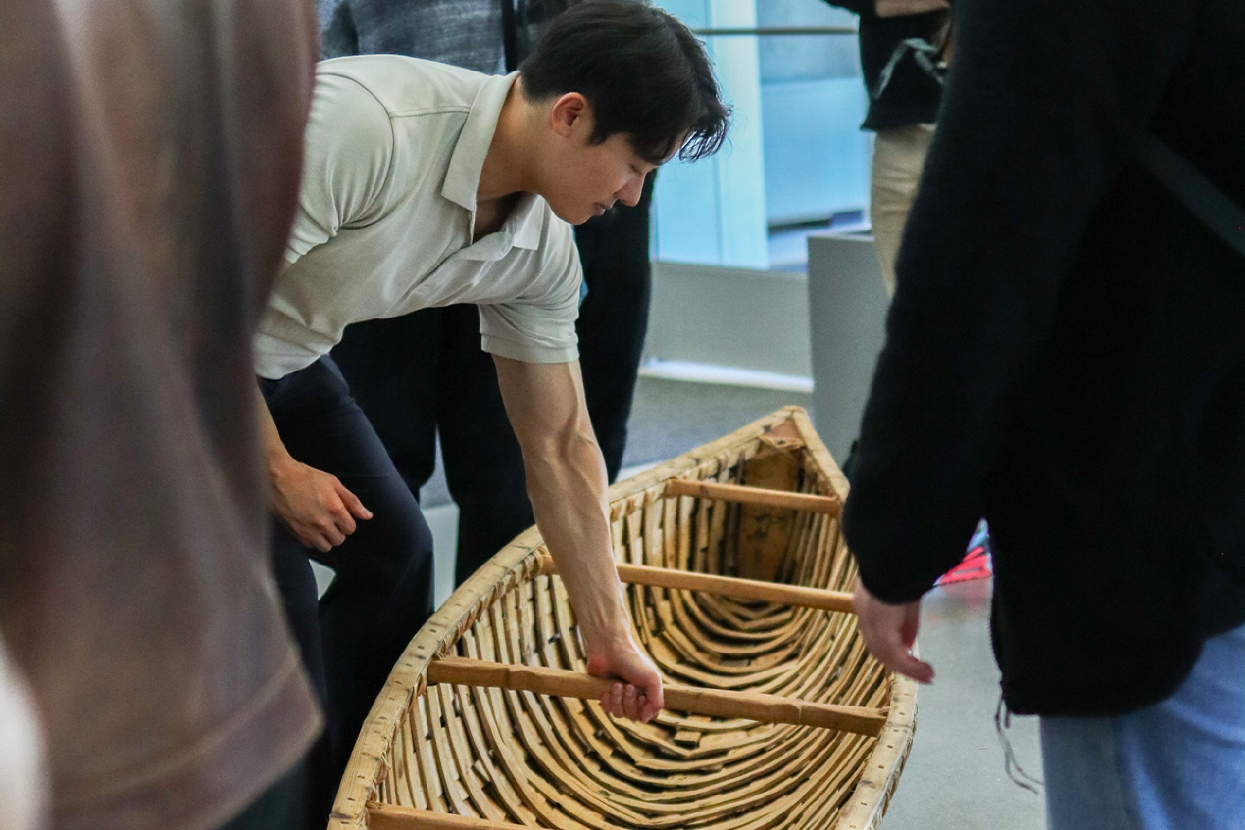 A student leans over to look at the handmade birch bark canoe in the Agora.