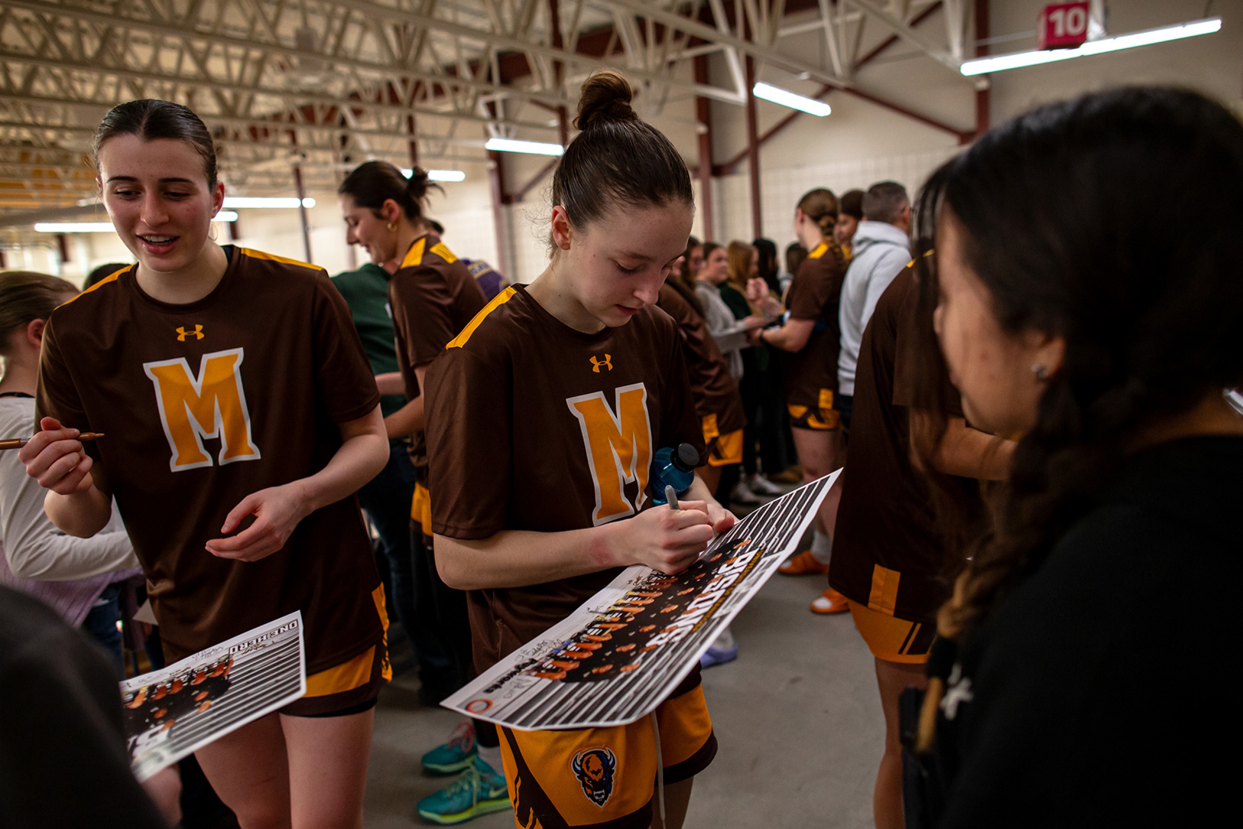 Bisons women's basketball players sign autographs after a game.