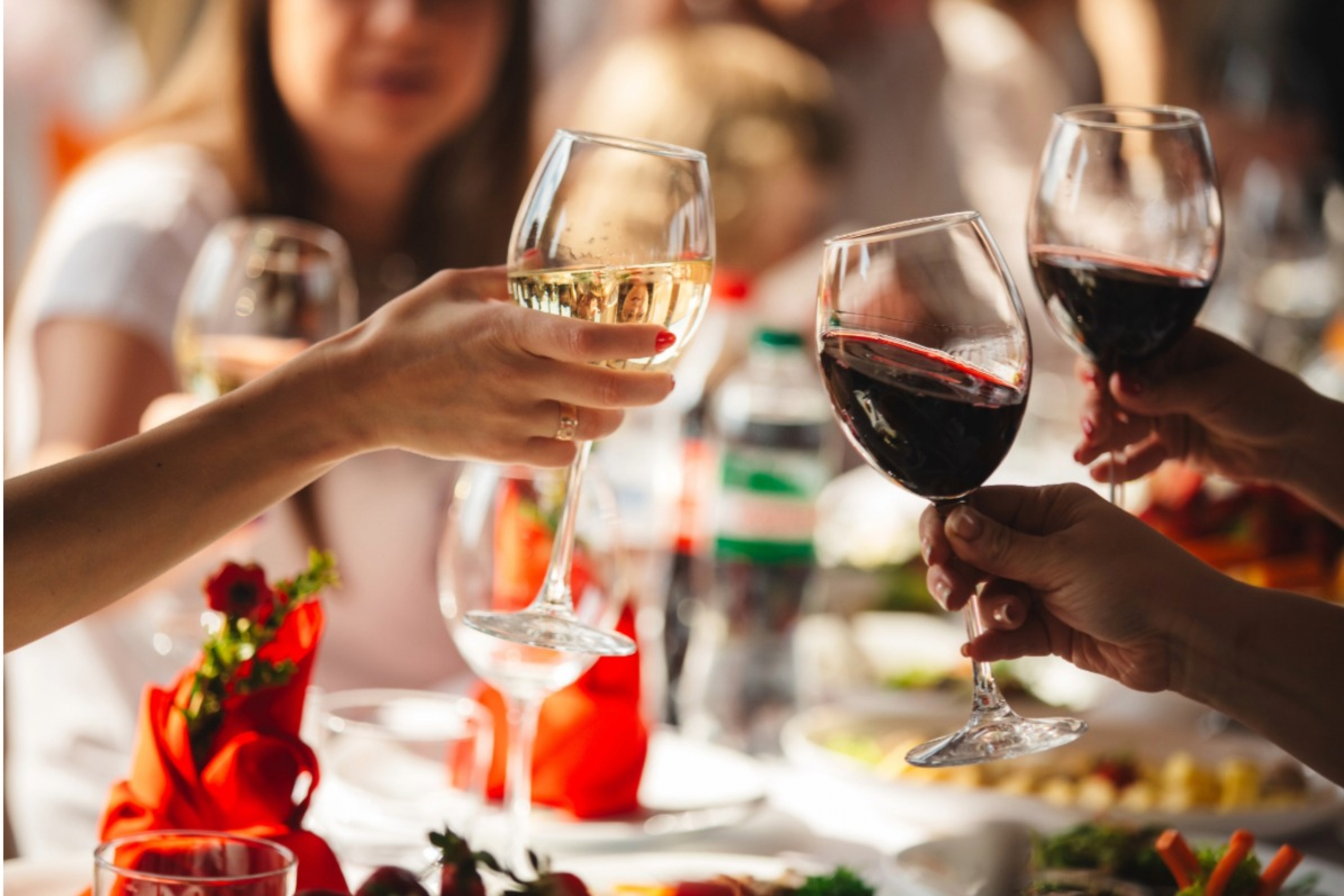 Hands lift wine glasses.