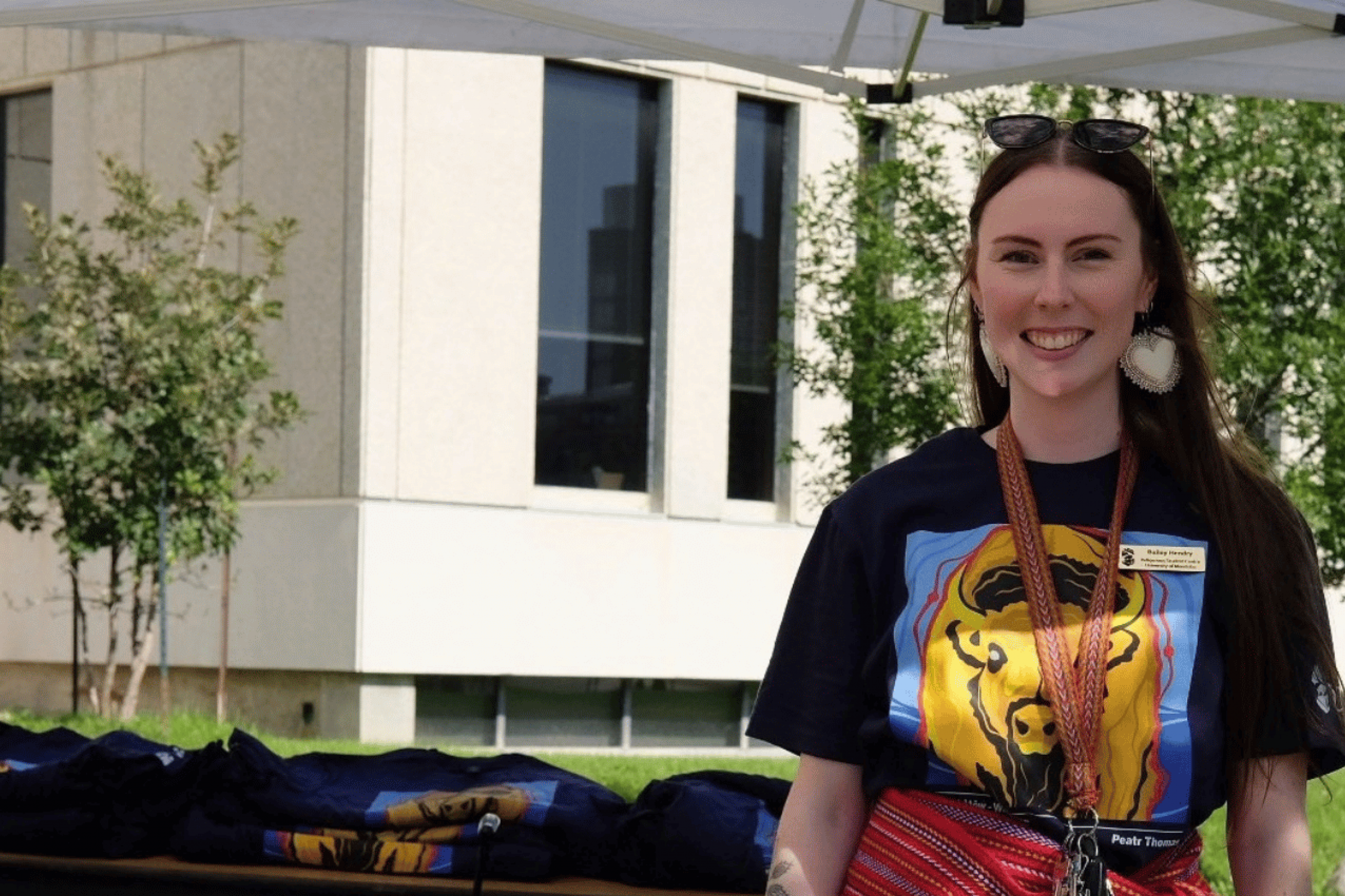 Bailey Pigeau smiles at an outdoor information table during 2025 Indigenous Orietation.