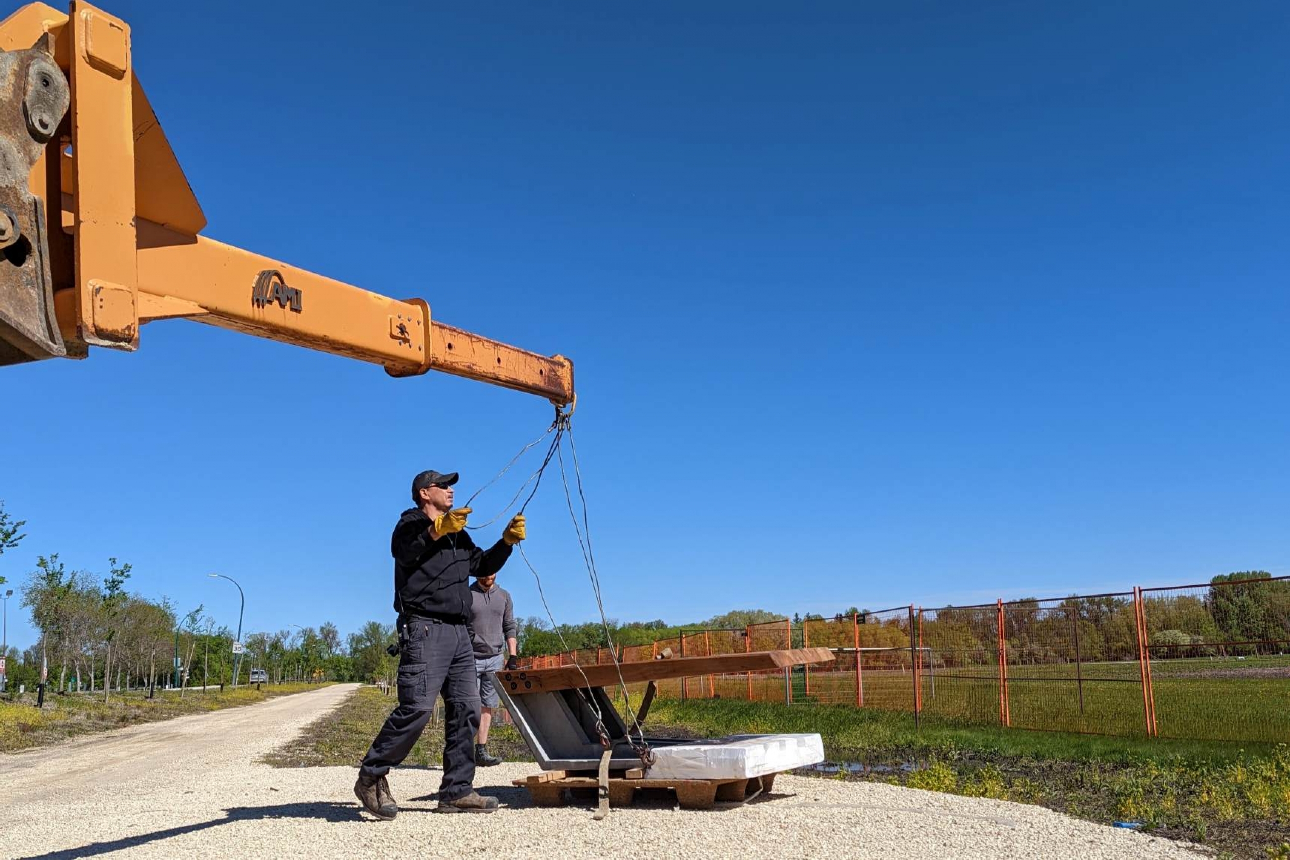 A bench being installed on a gravel pathway.