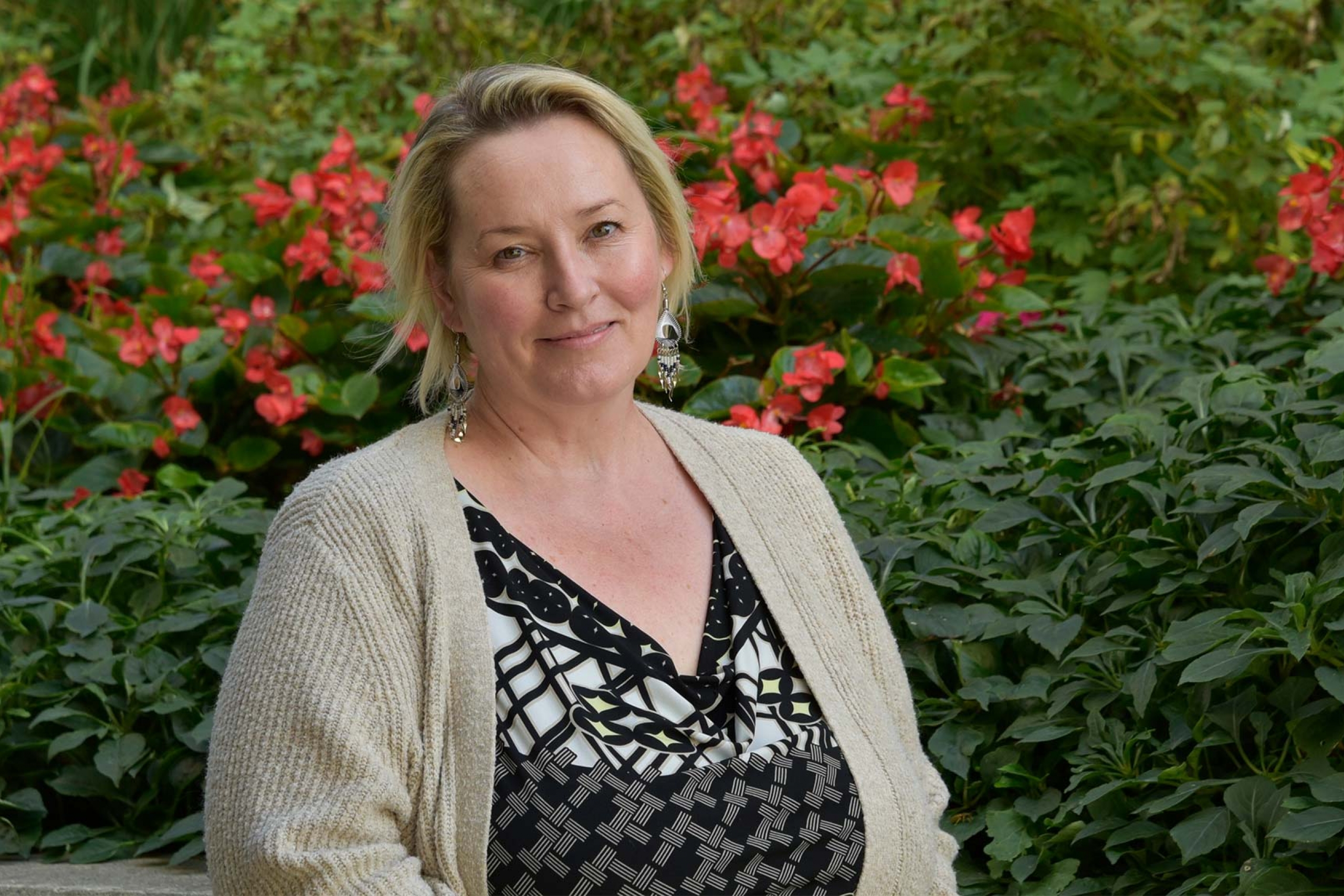 Dr. Carrie Selin wearing a black patterned shirt with a white cardigan smiling at the camera.