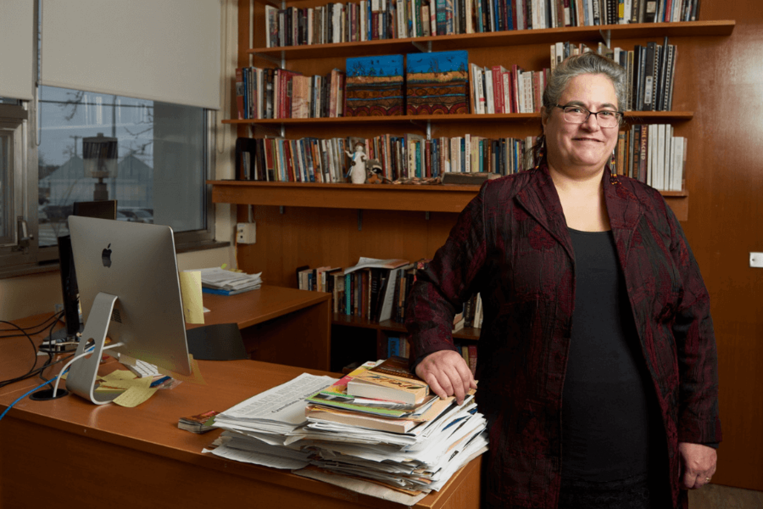Dr. Cary Miller smiles while posed in front of bookcase and desk