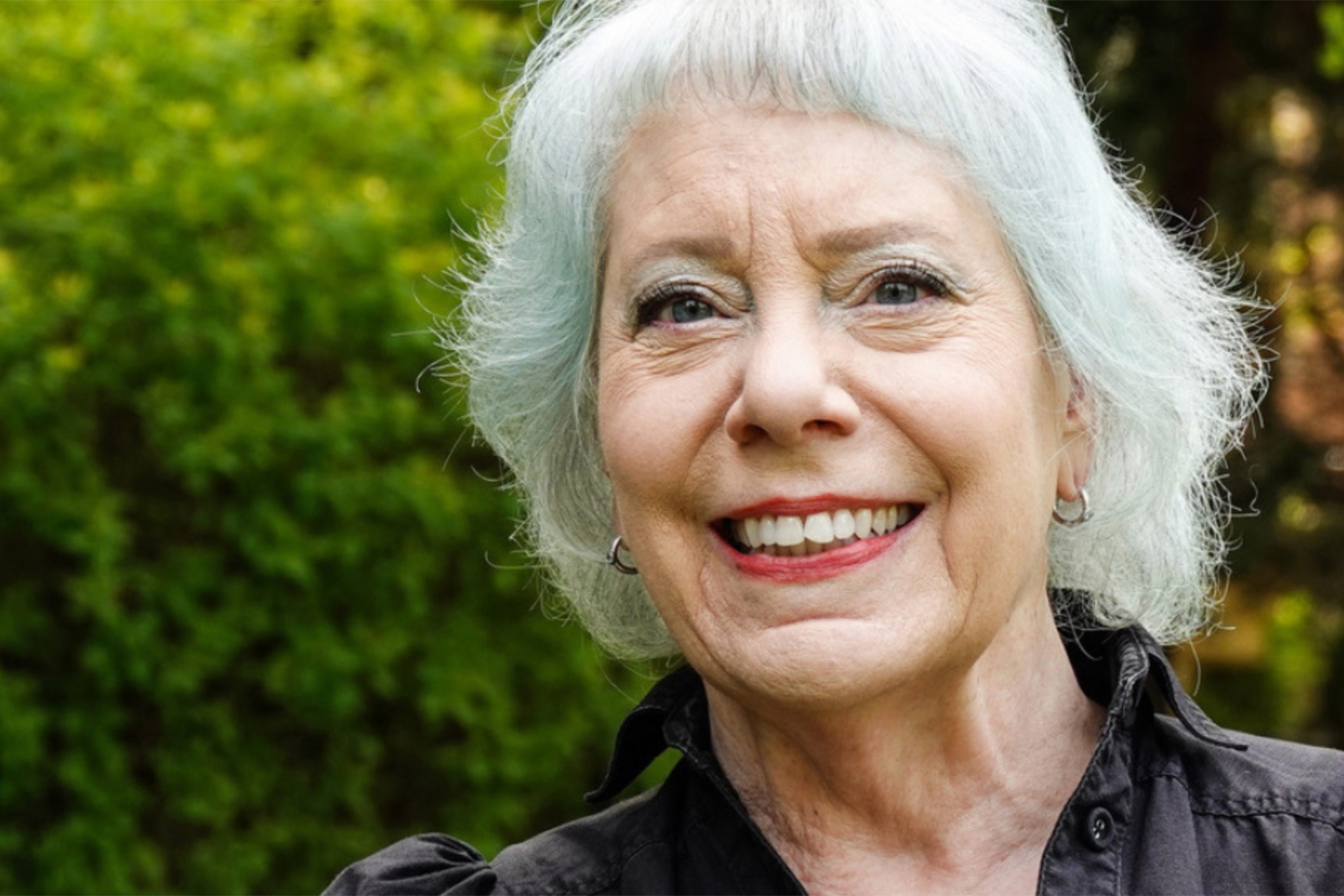 Jayanne English wearing a black collared shirt smiling at the camera.