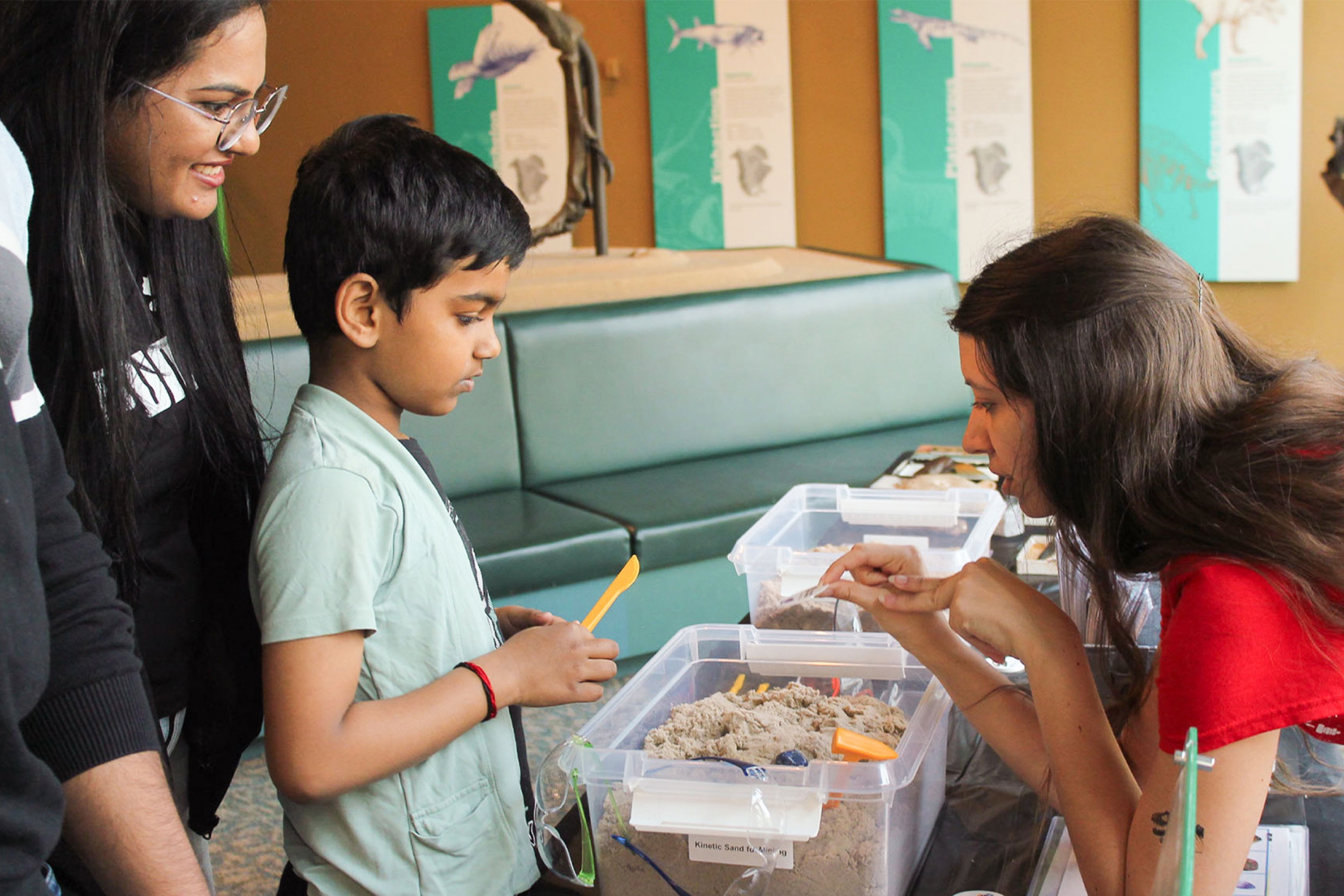 A kid touching some sand in the Cretaceous Menagerie.