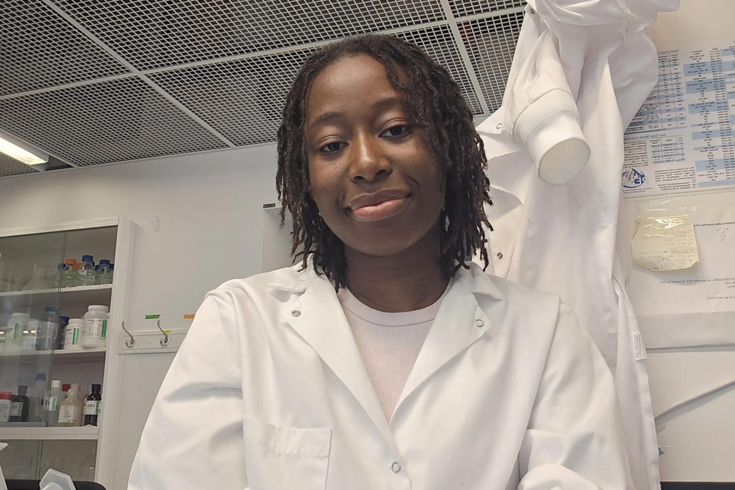 Deborah Owoyemi wearing a lab coat and smiling at the camera.