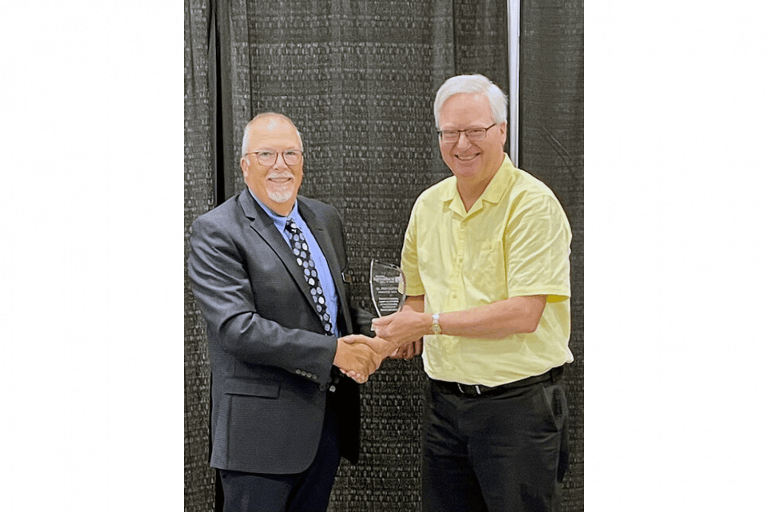 Don Flaten shaking a man's hand as he is being presented with an award.