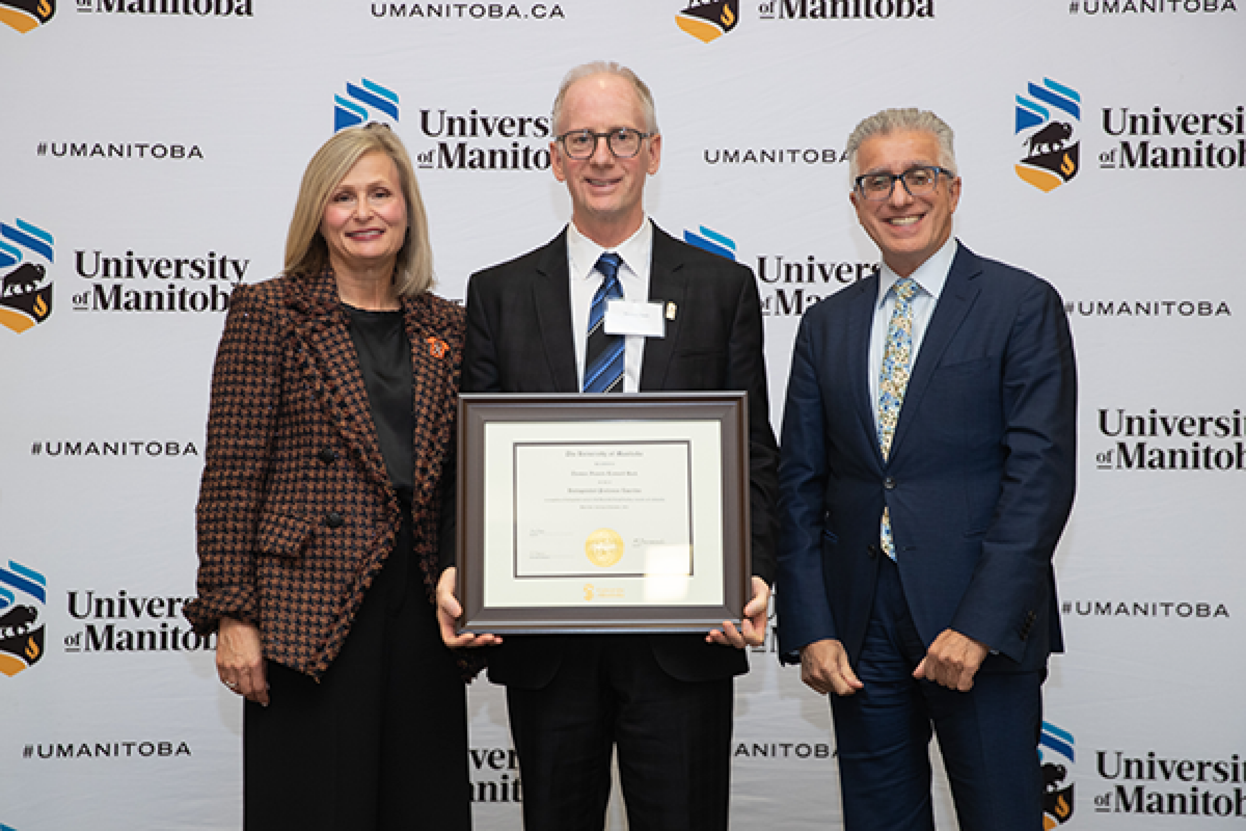 Dr. Thomas Hack receives emeritus certificate from Chancellor Mahon and President Benarroch.