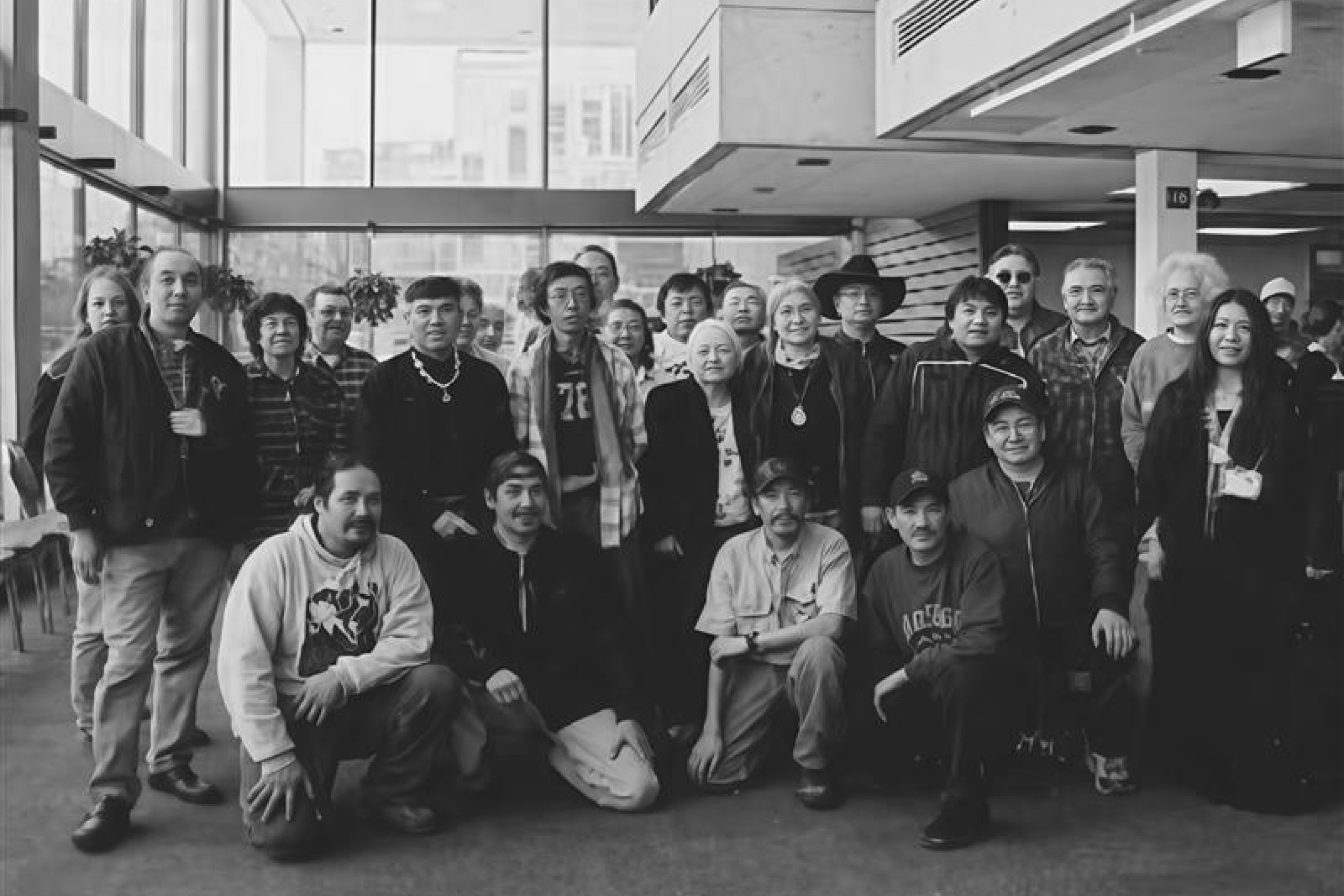 A large group of people posing together indoors, with some standing and others kneeling in front.