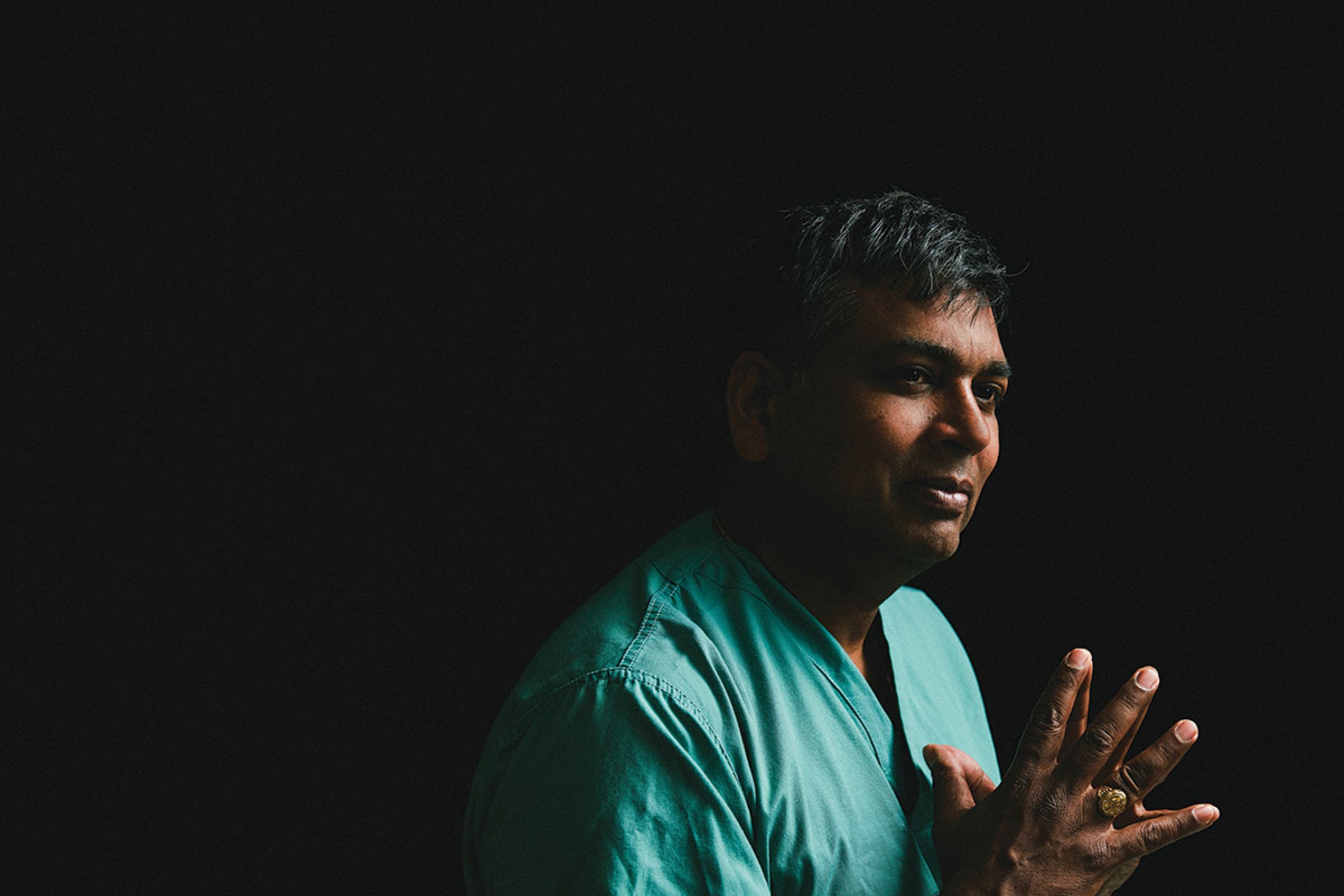 A man in scrubs against a black background.