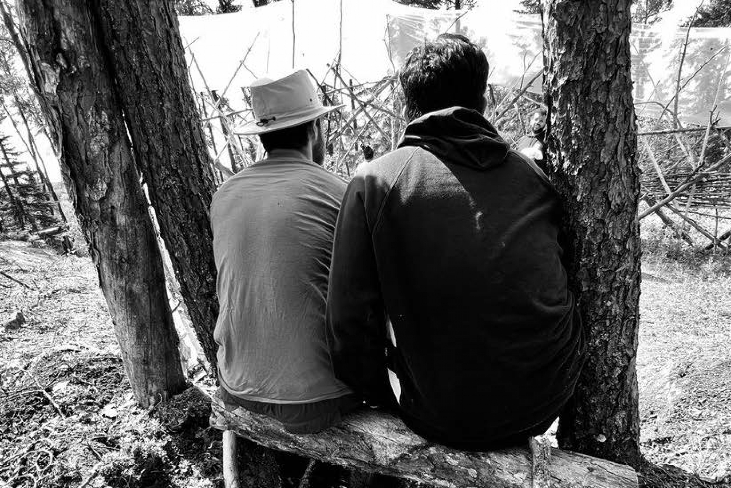two people taking a break from work sitting on a tree bench outside