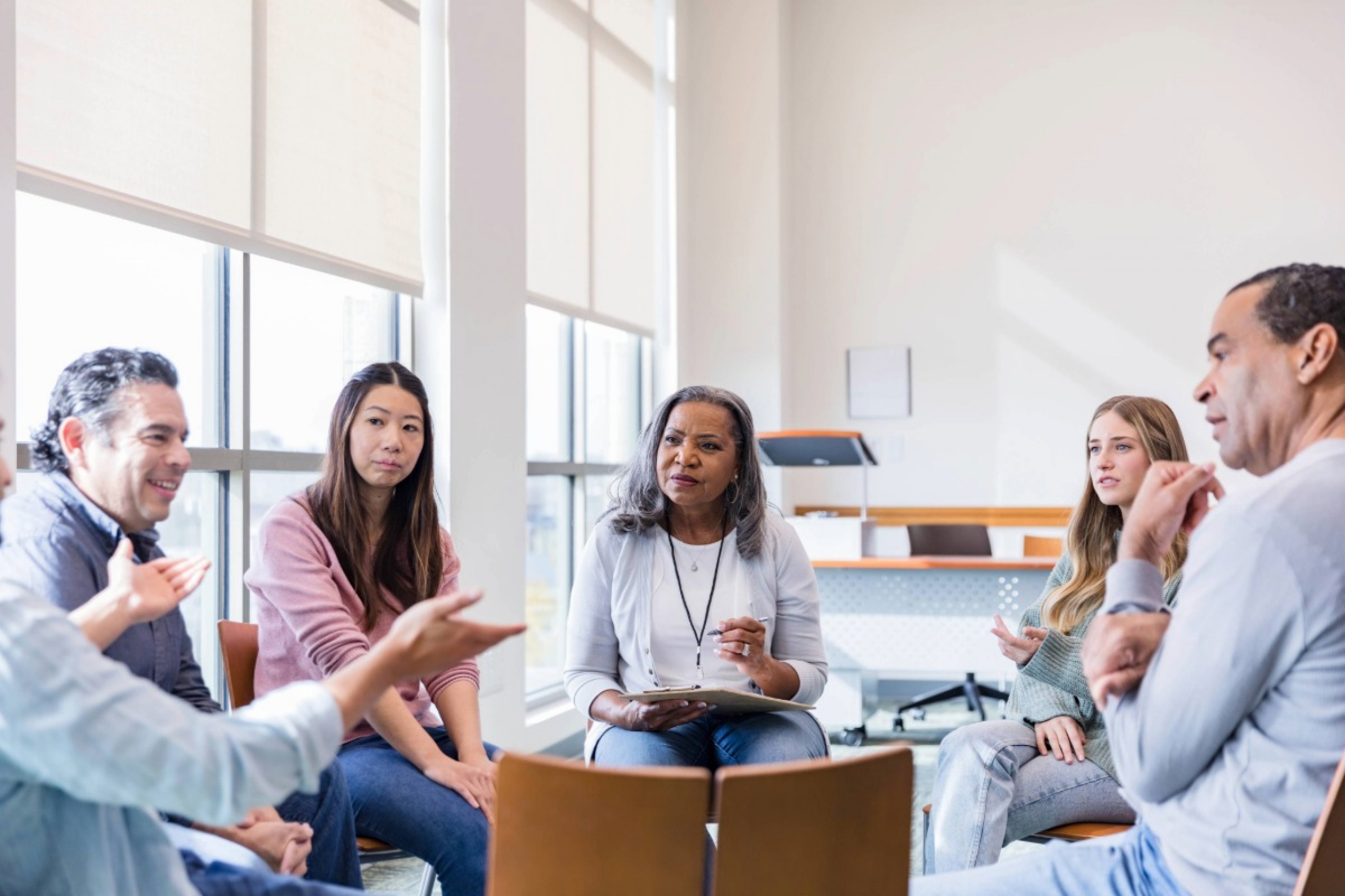 Group session; diverse adults share experiences and support each other.