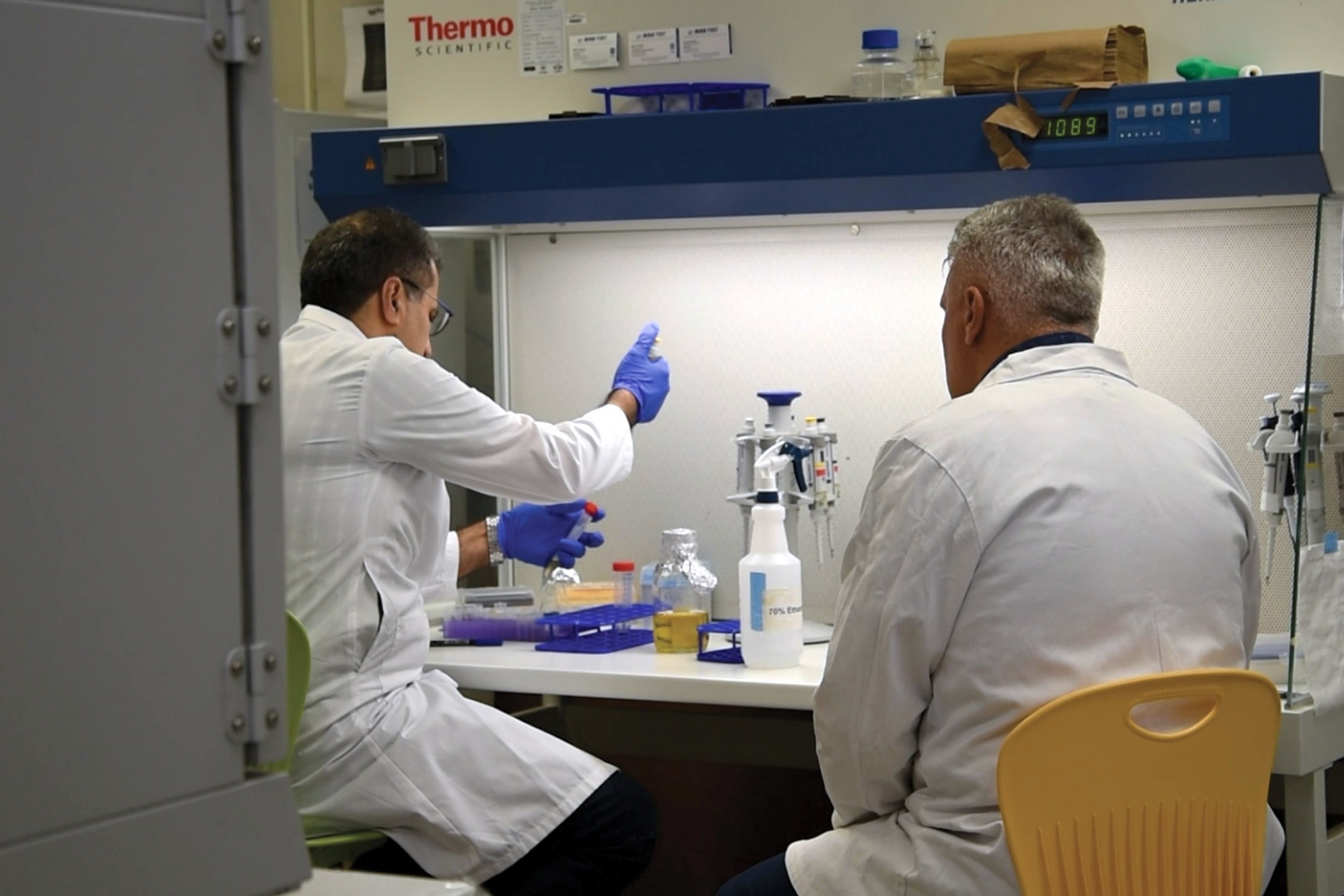 Hamid pipetting while talking to Ned.