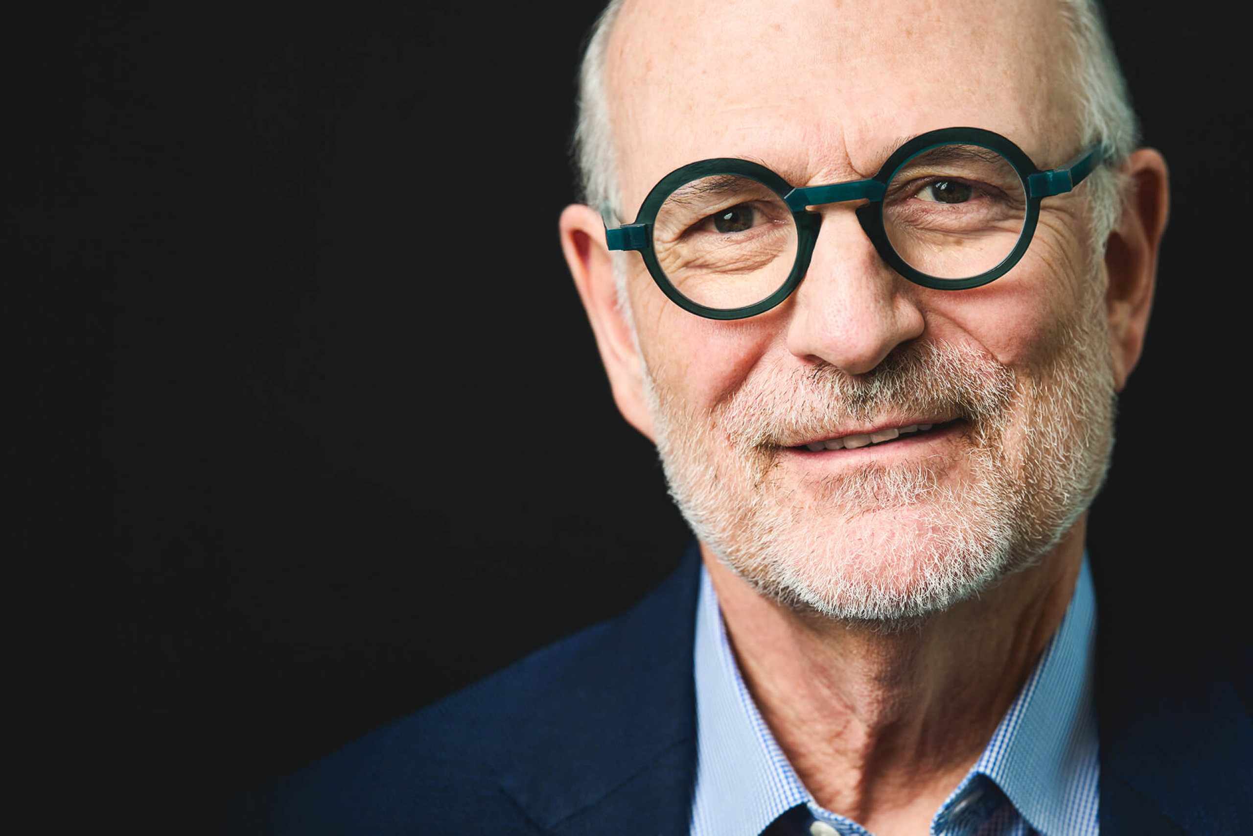 Harvey Chovinov, on a black background, looking at the camera