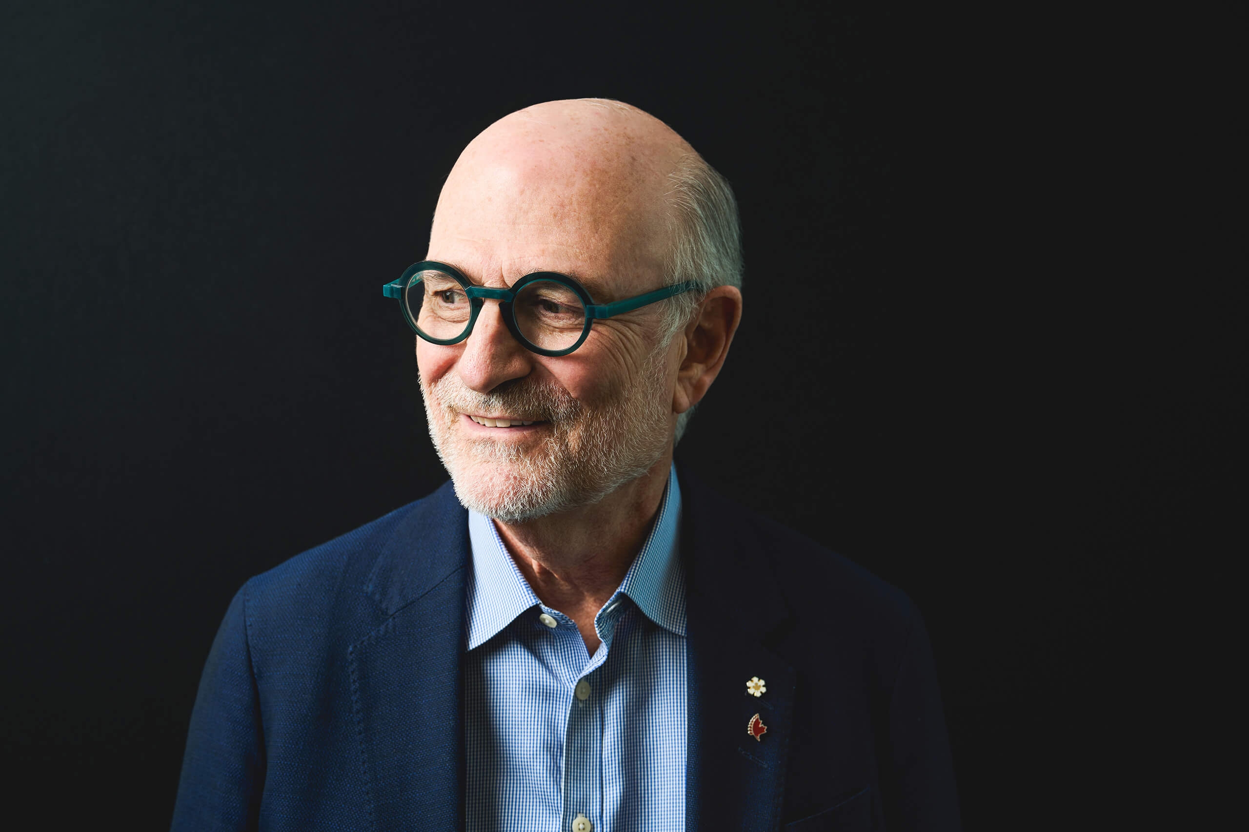 A man in a suit on a black background, looking off to the side