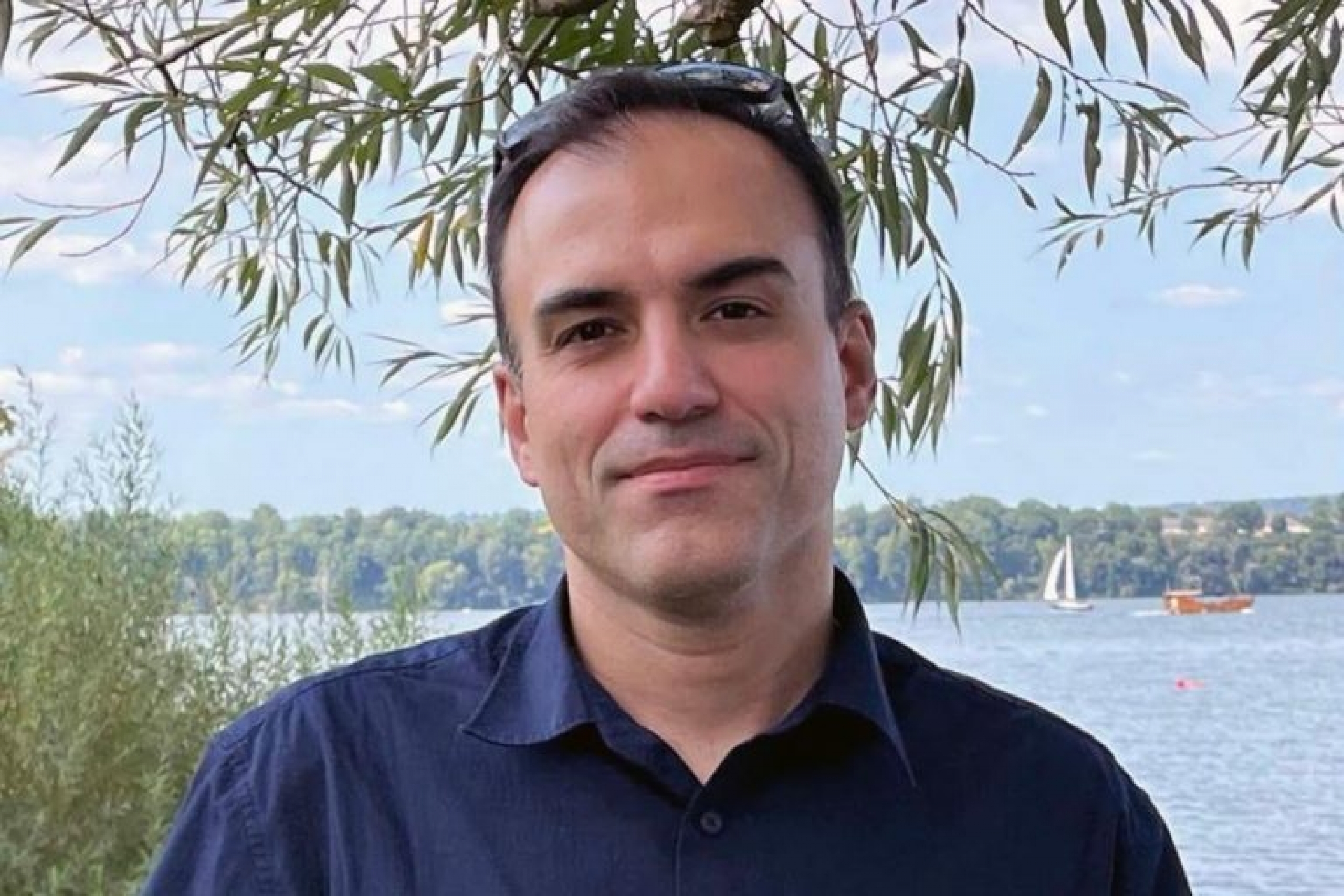 A man (Dr. Hooman Derakhshani) stands under a tree