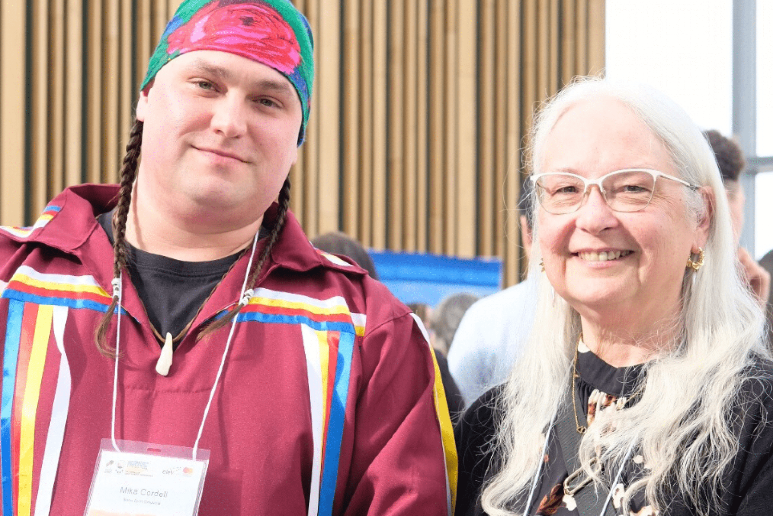 Two attendees stand side by side and smile at the camera during the event.
