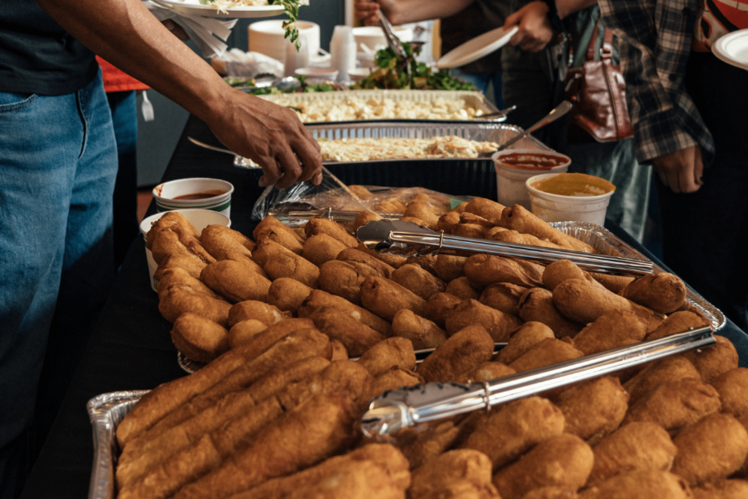 A close-up view of the feast table at UM Indigenous Student Orientation, featuring trays of bannock dogs and traditional dishes served buffet-style.