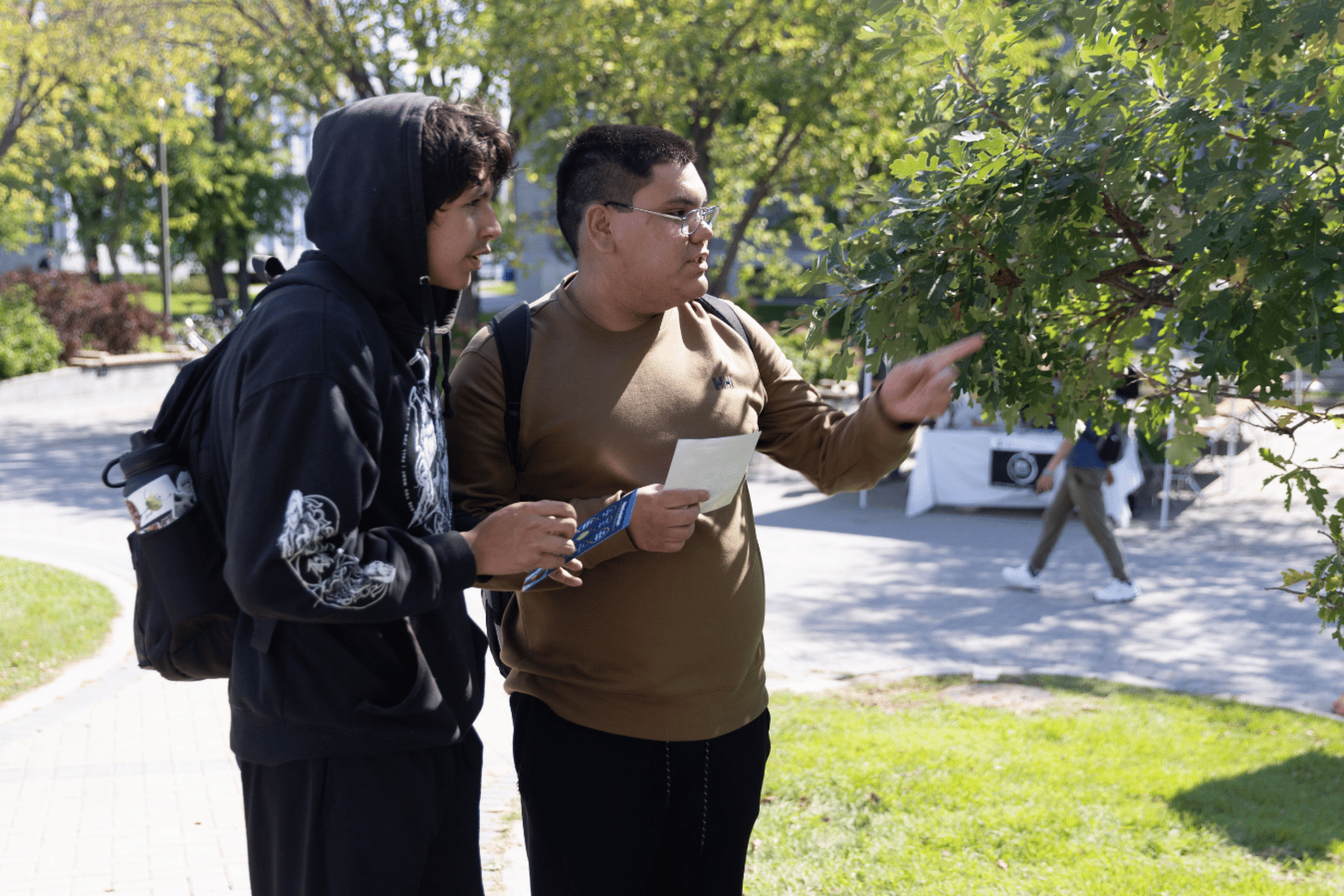 Two students look at event materials and booths outdoors.
