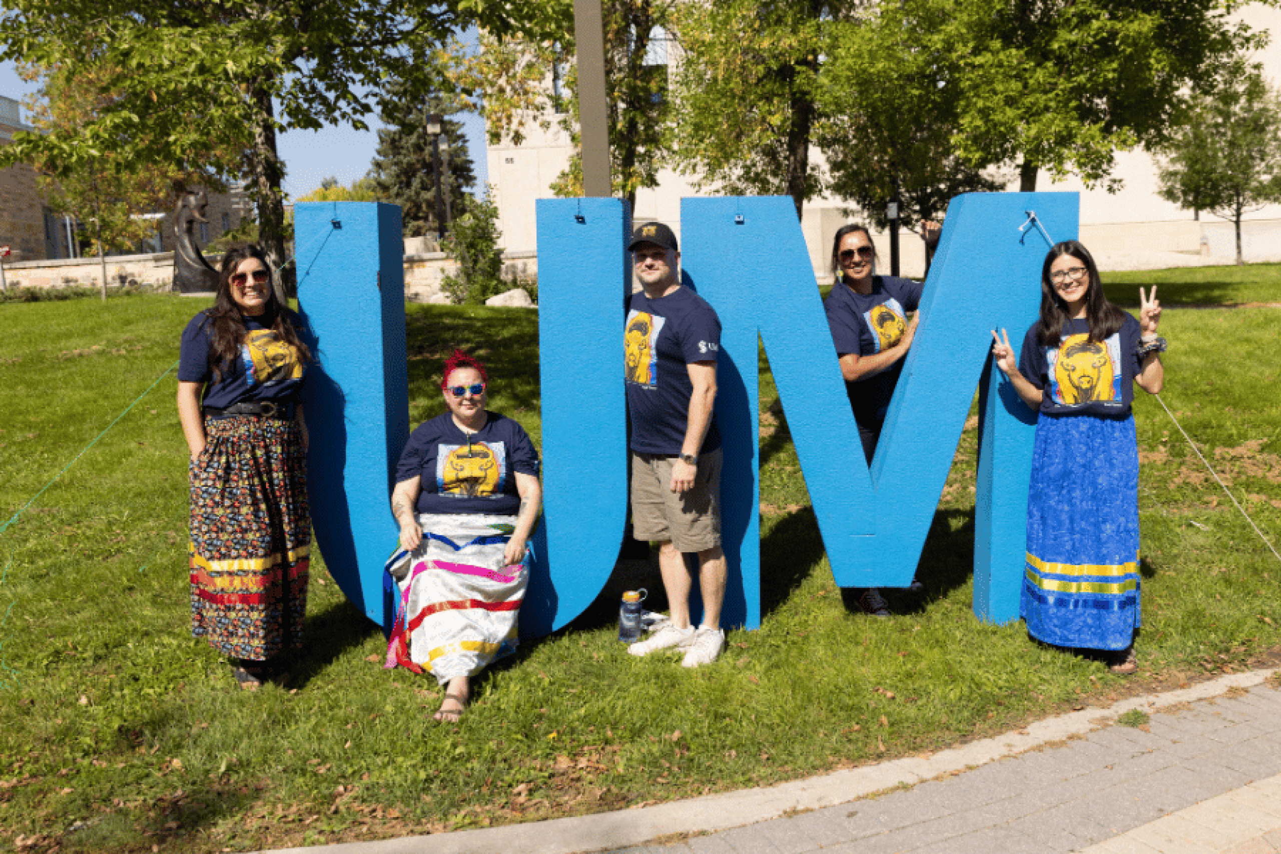 2. Indigenous Orientation participants posing beside a large UM sign outdoors.