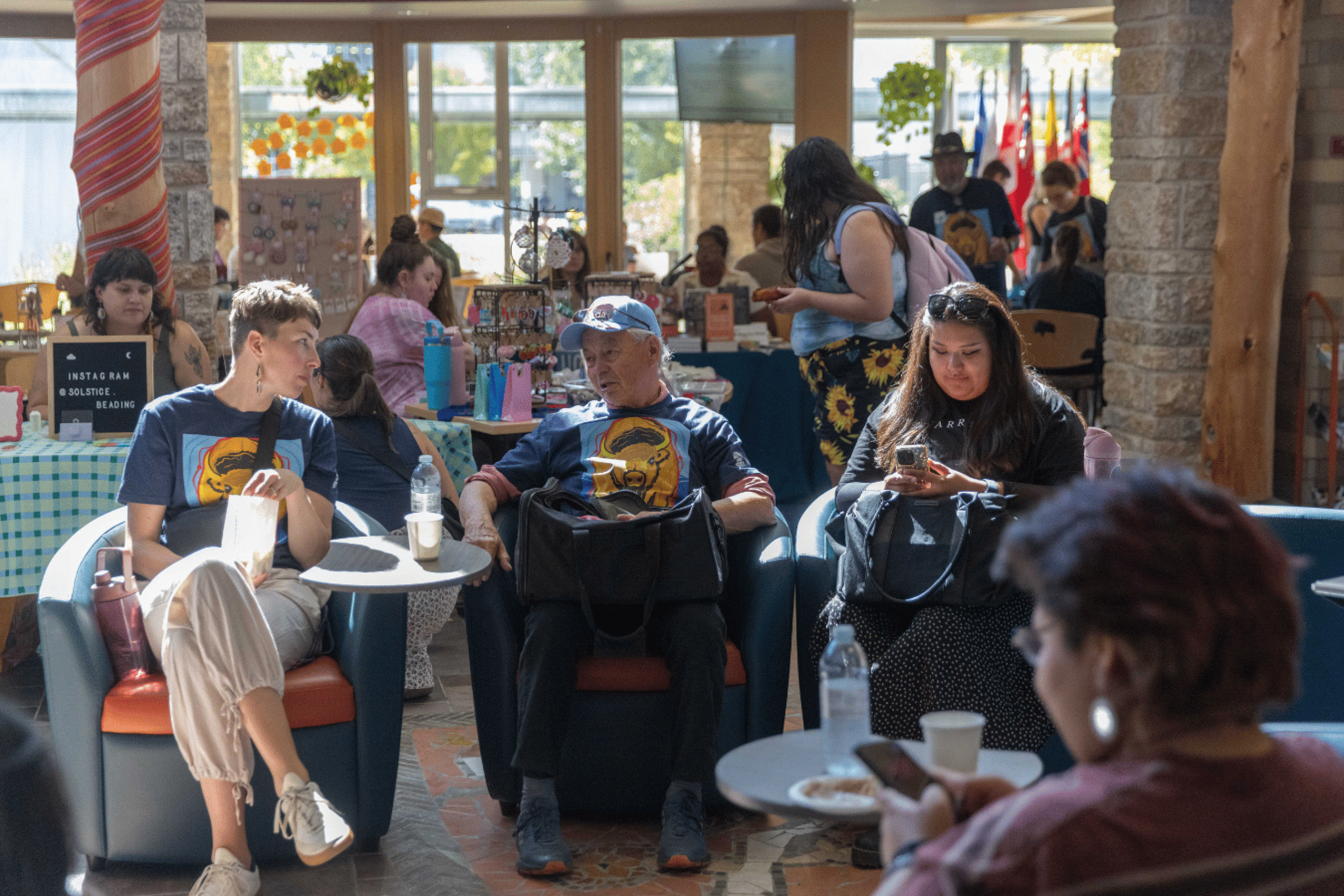 Attendees gather among vendor tables inside Migizii Agamik and talk to an Elder.