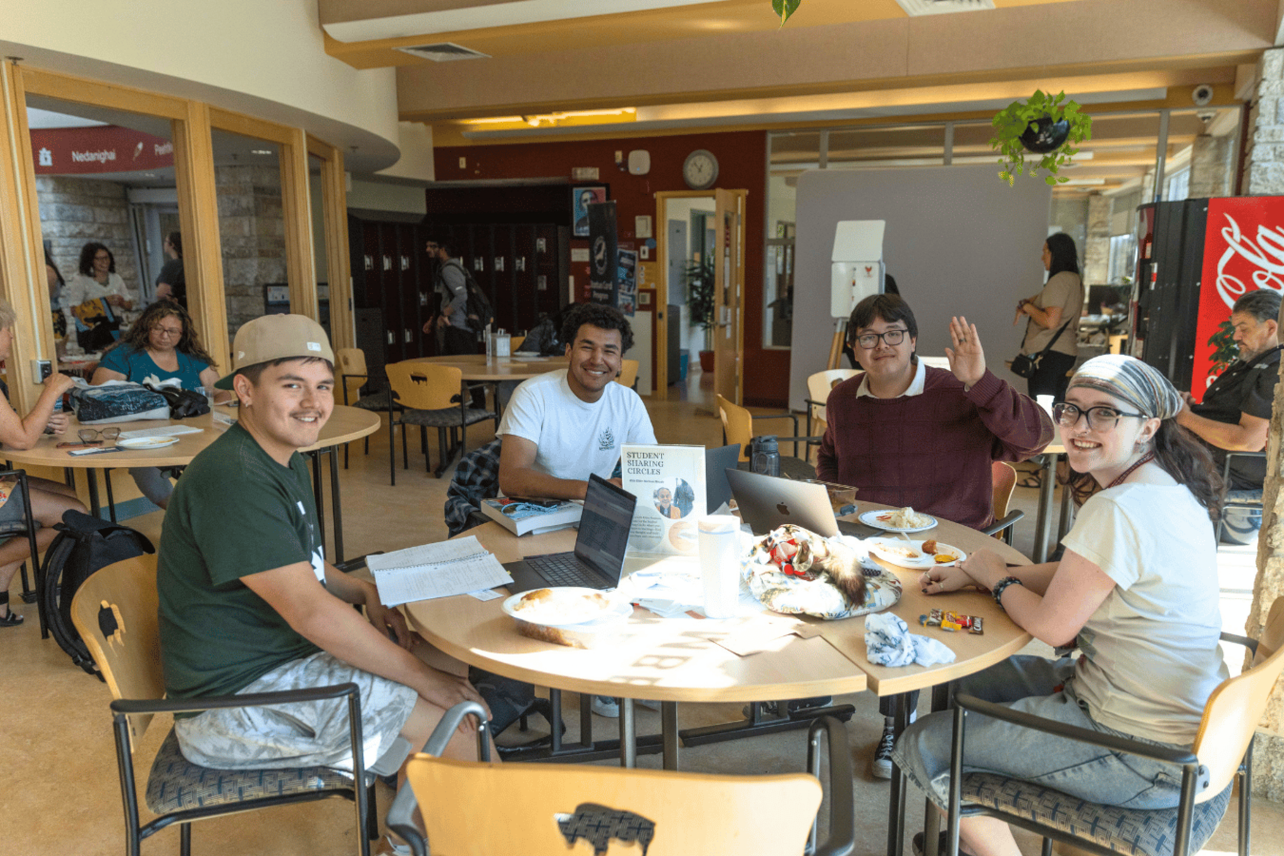 Four students sit together around a table inside Migizii Agamik.