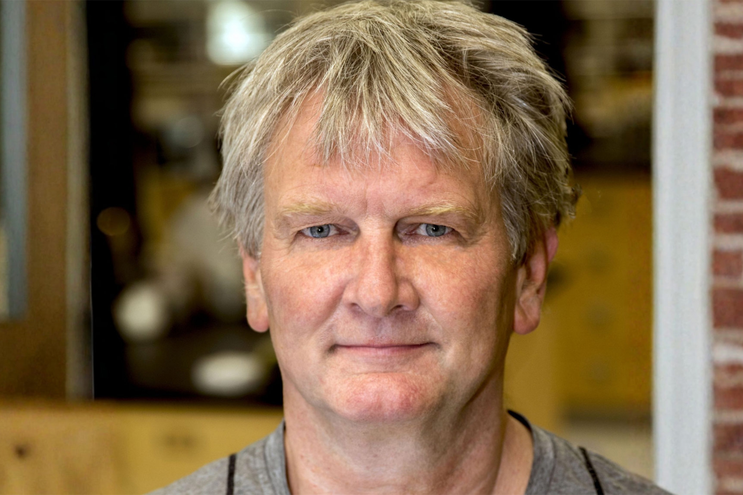 Jörg Stetefeld wearing a gray shirt and smiling at the camera.