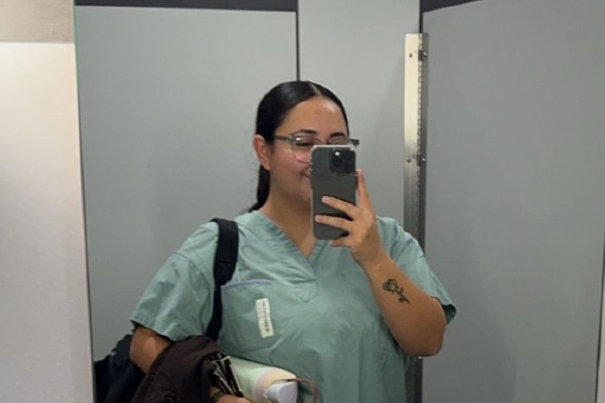 A student nurse takes a selfie in a bathroom mirror.