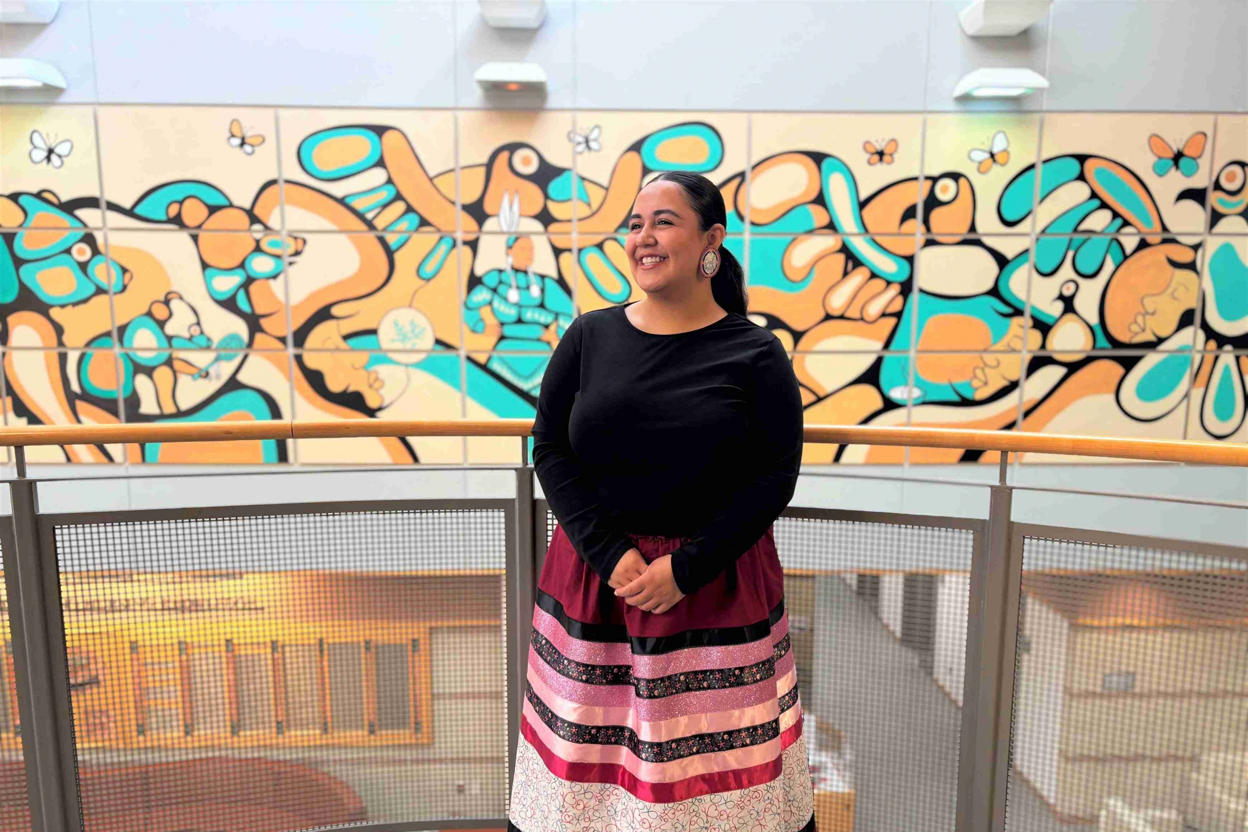 Woman wearing ribbon skirt stands proudly.