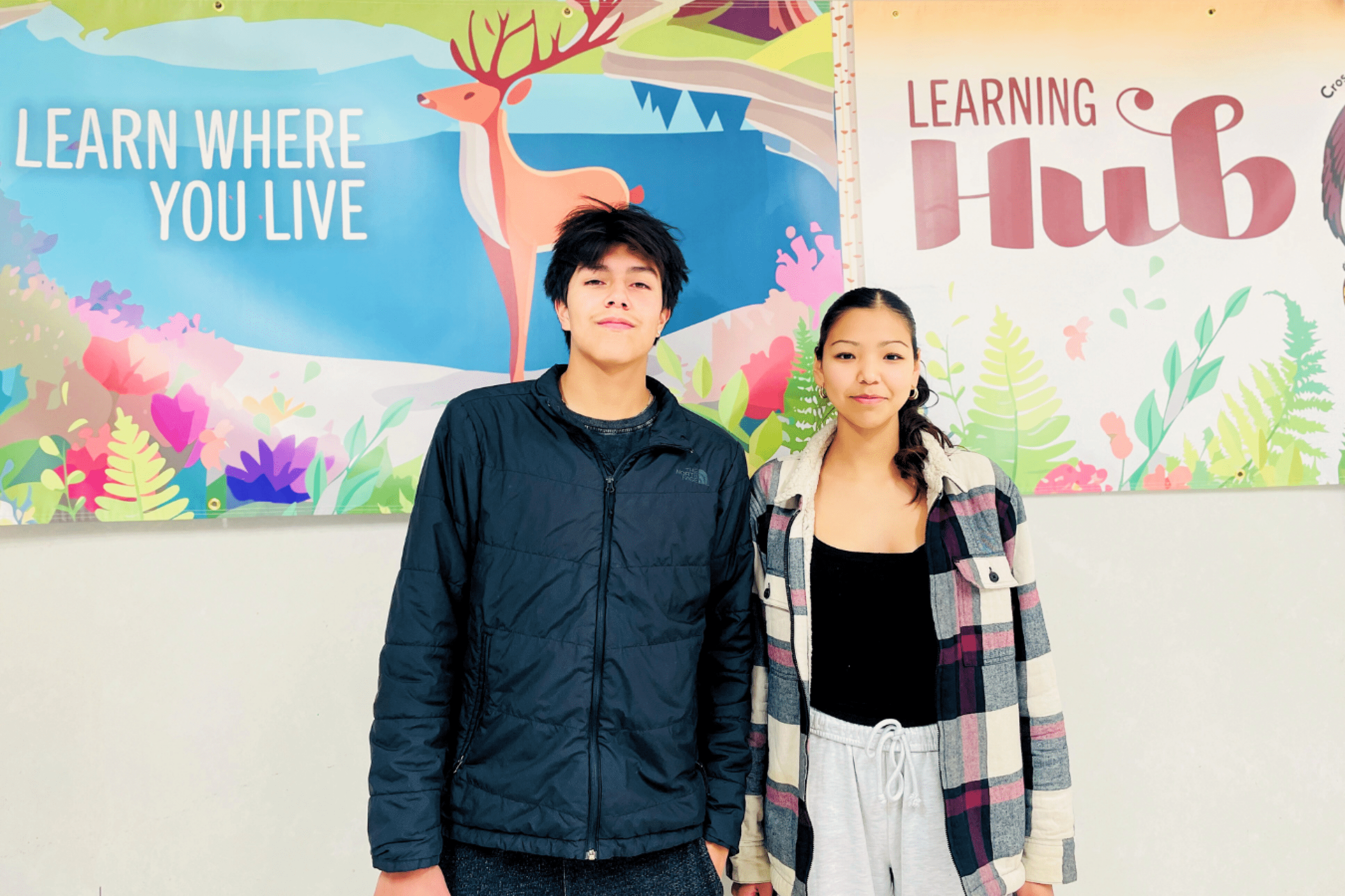 Two students standing in front of a “Learning Hub” sign.