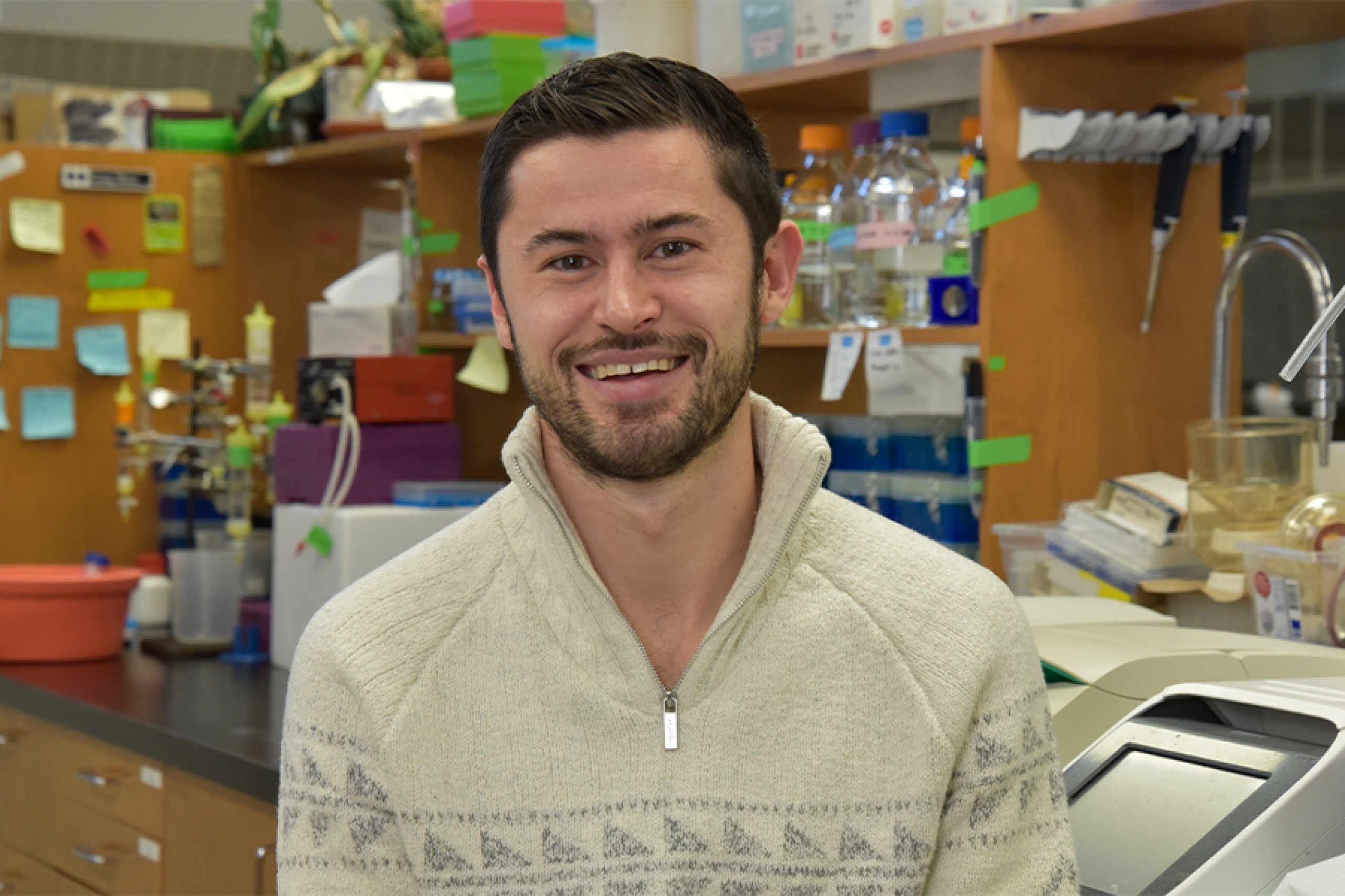 Matthew Van Schepdael wearing an off-white sweater smiling at the camera.
