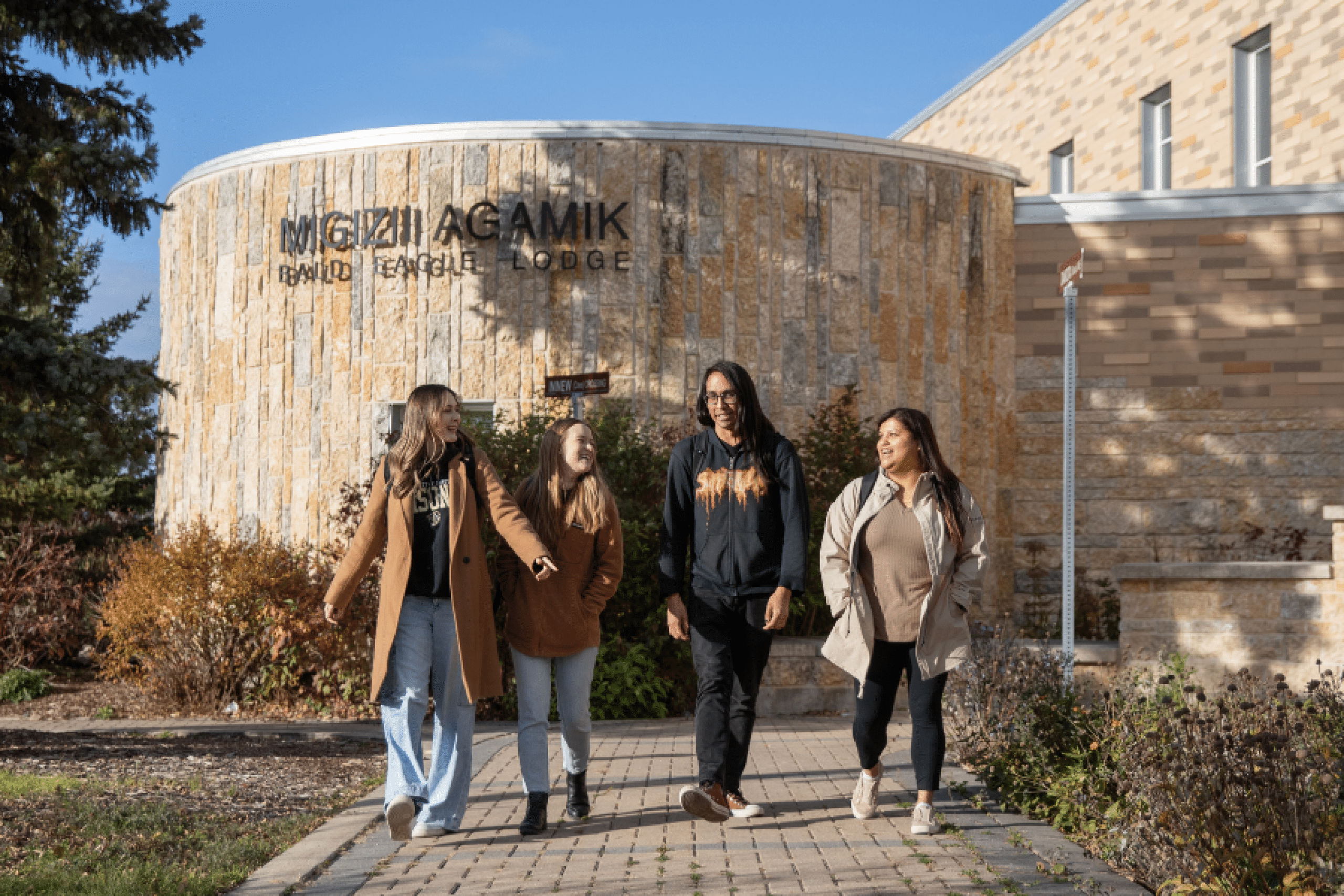 Four students walk together outside Migizii Agamik – Bald Eagle Lodge.
