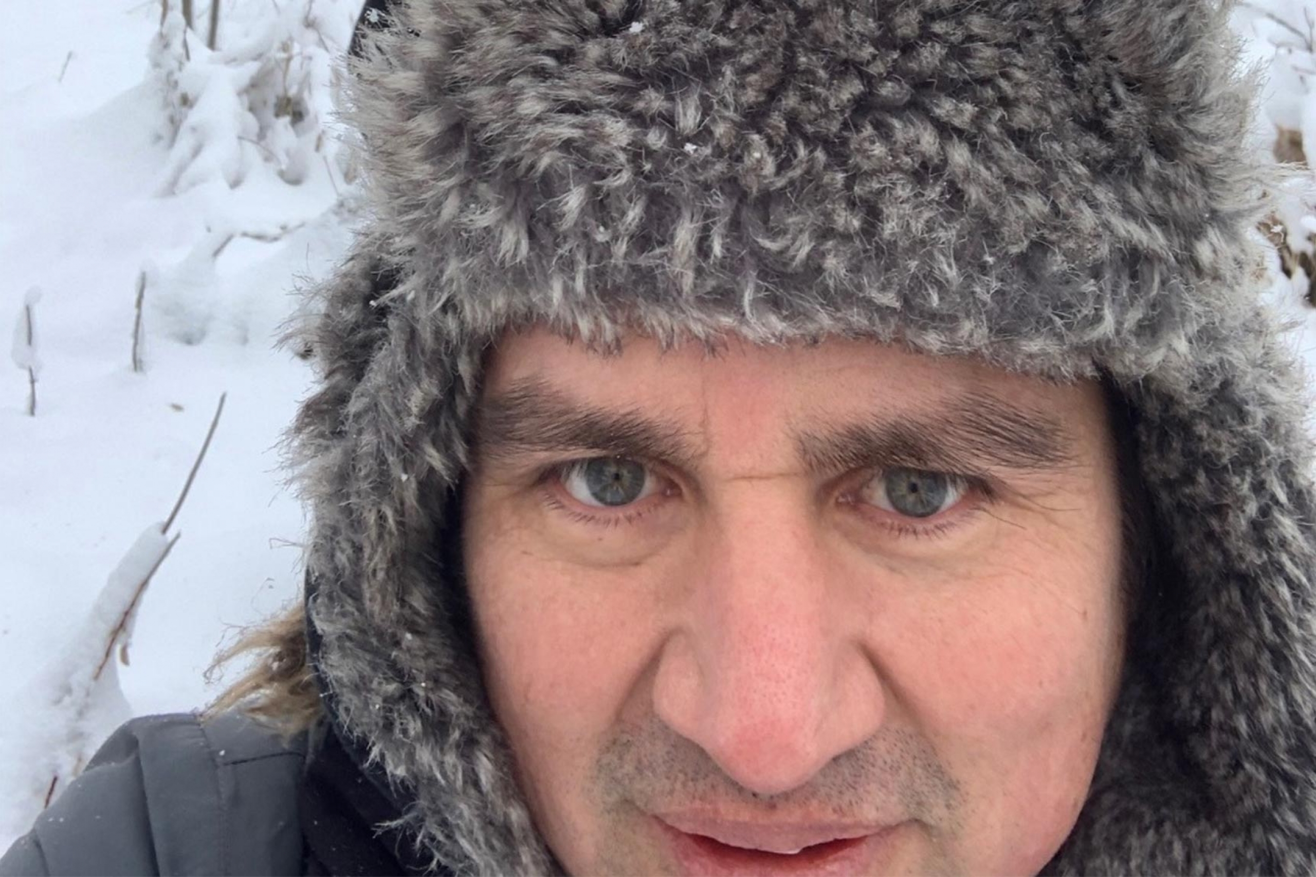 Miguel Uyaguari in the field in winter with a student in the background.