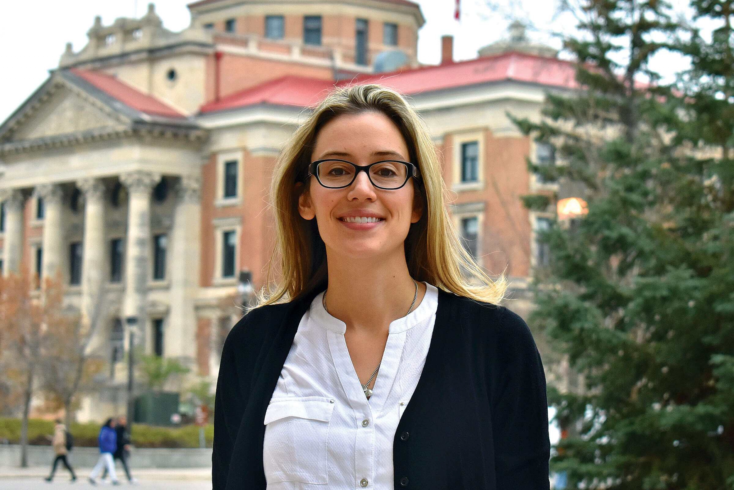 Woman stands outside infront of a building.