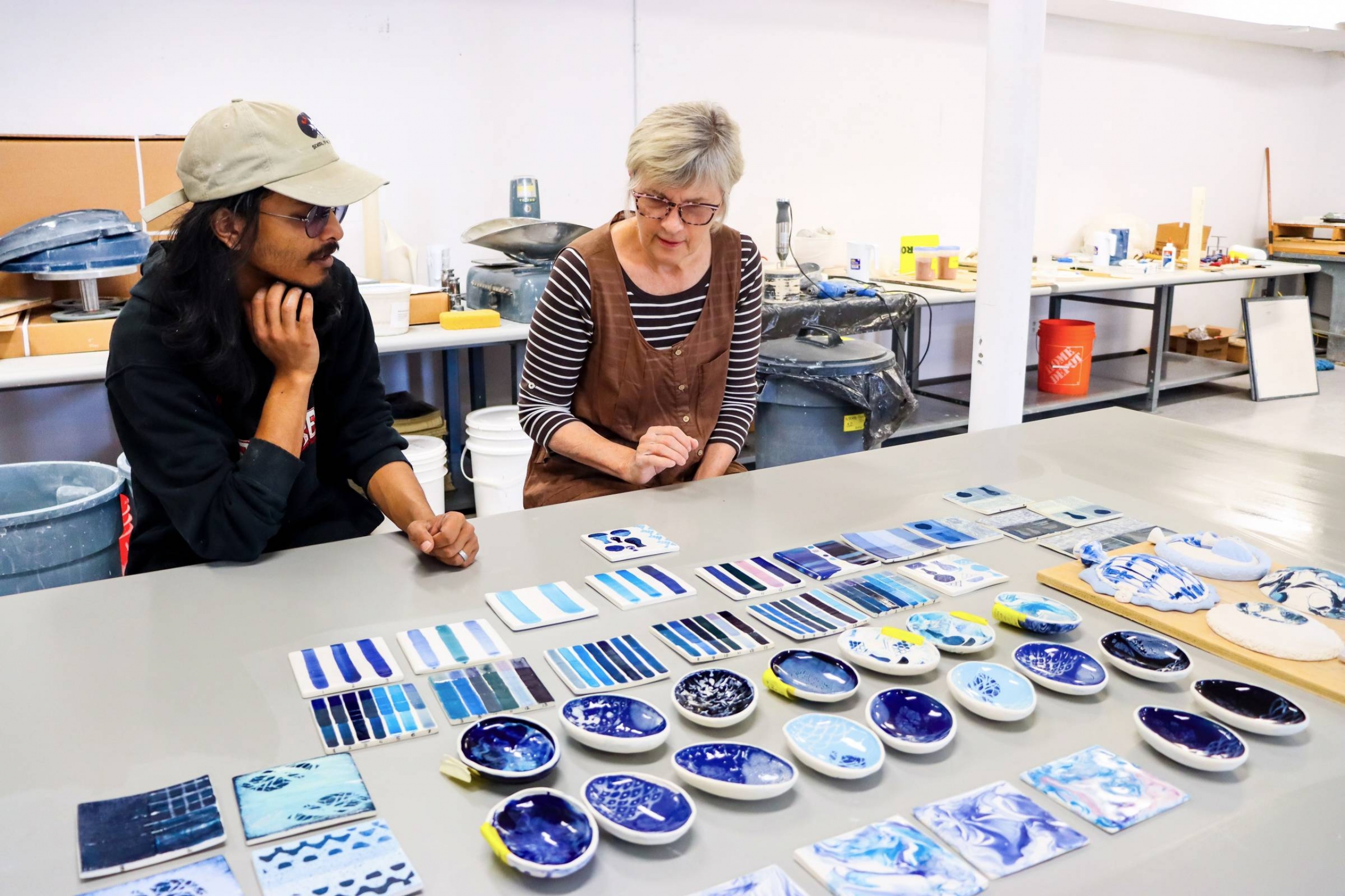 Grace Nickel and Abtahi Hassan looking at ceramics pieces with different shades on blue on them.