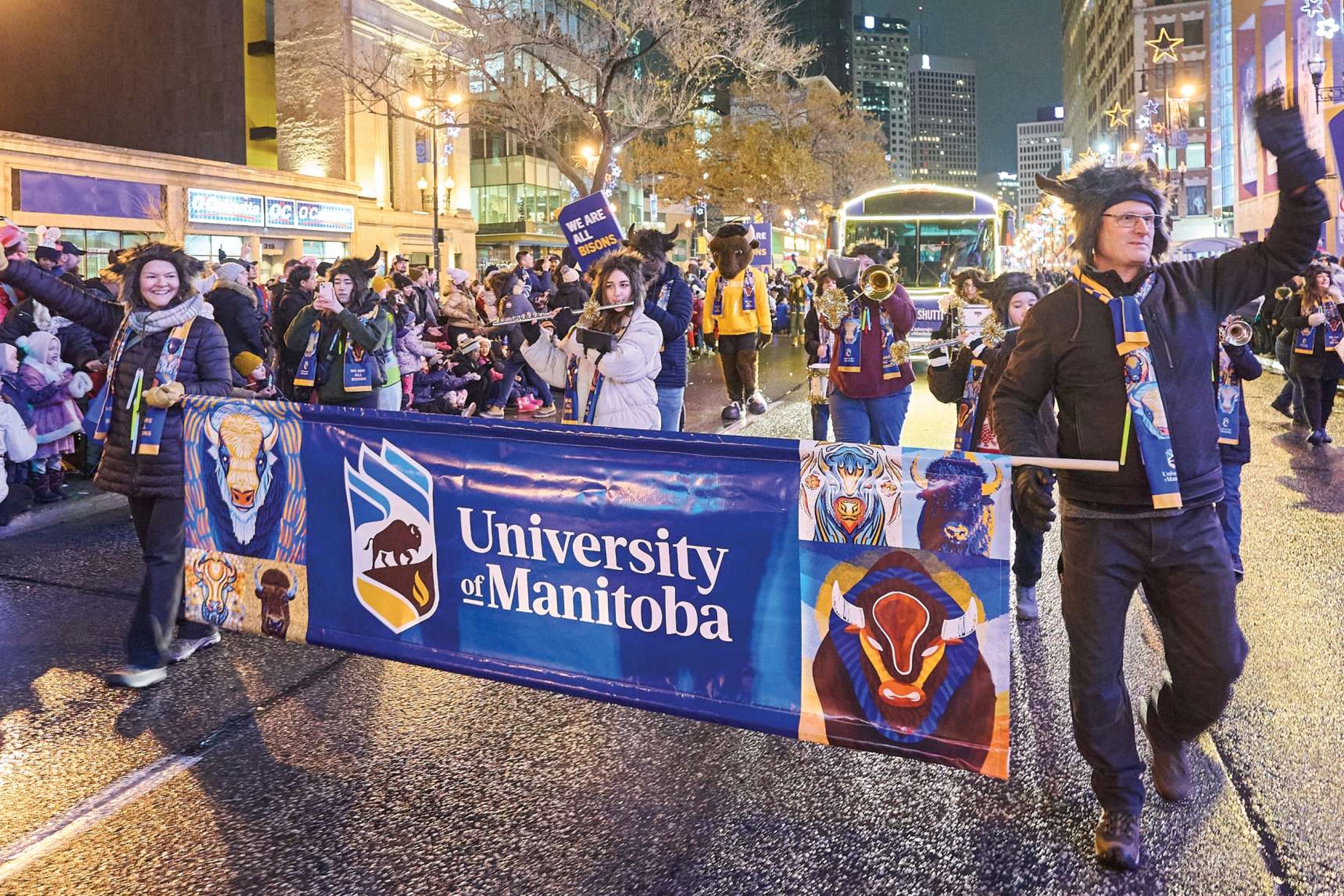 People walking with a University of Manitoba banner during the Santa Claus parade in Winnipeg.