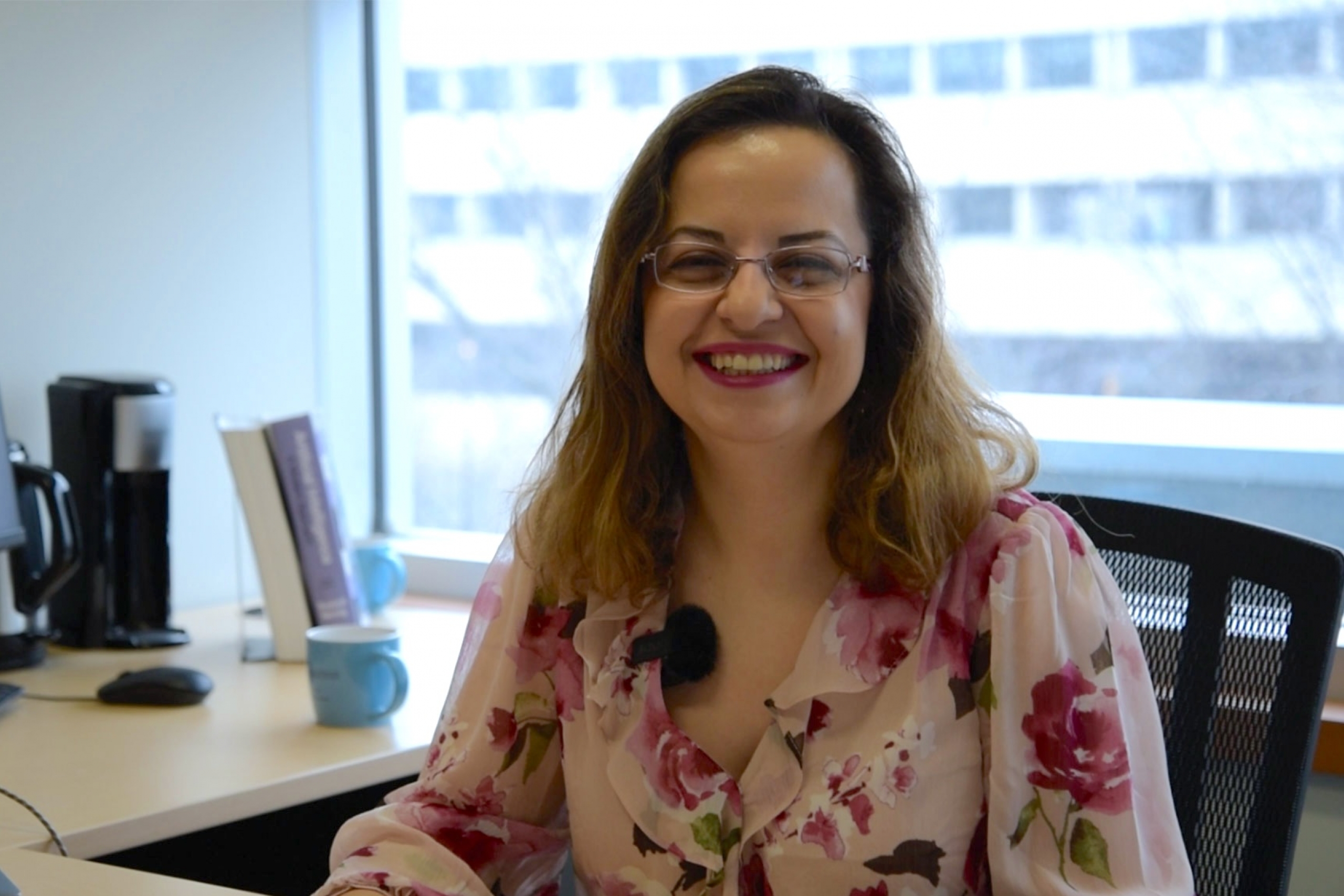 Sadaf Salehkalaibar wearing a floral button down shirt and smiling at the camera.
