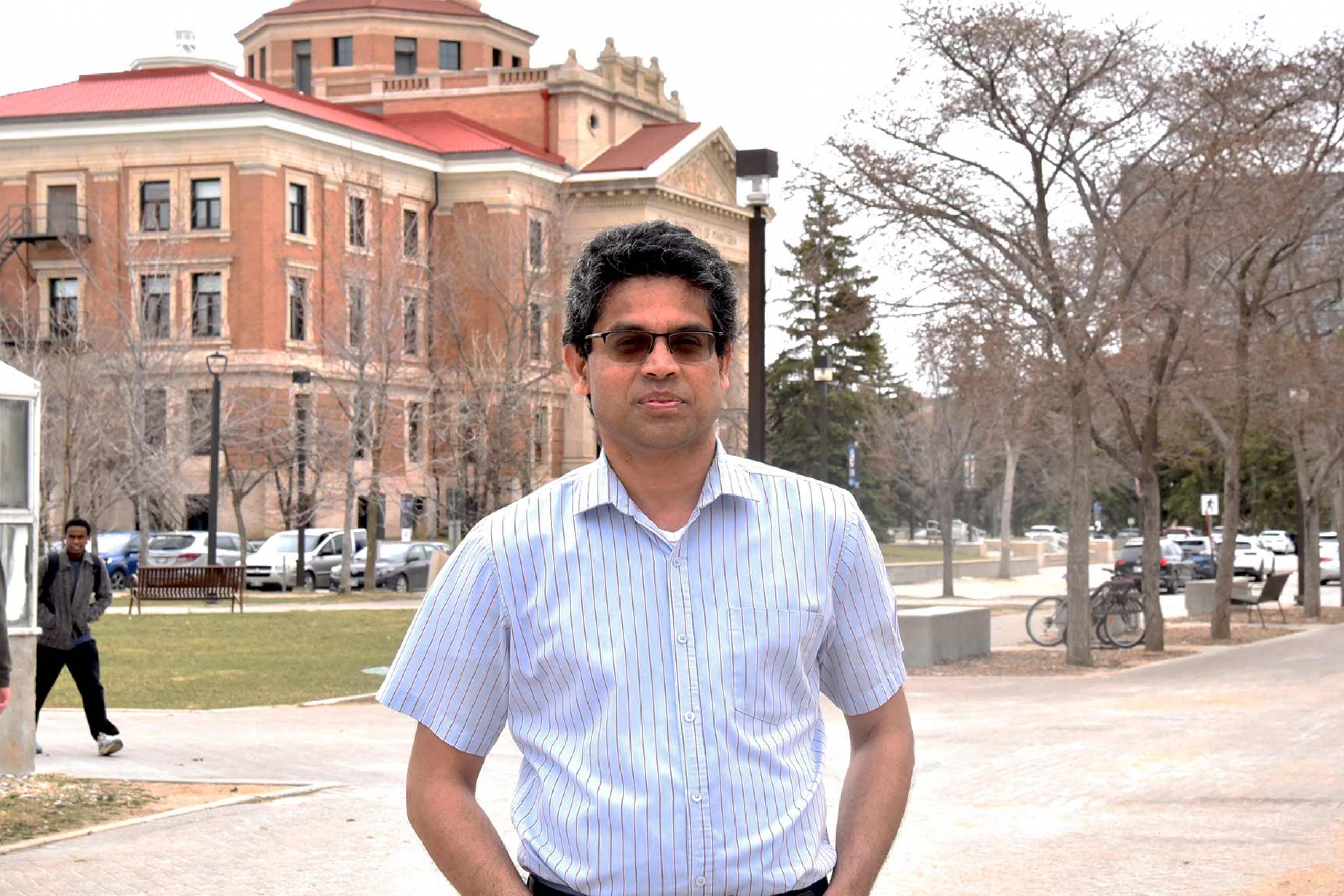 Saman Muthukumarana wearing a blue button down shirt with the admin building at the back.