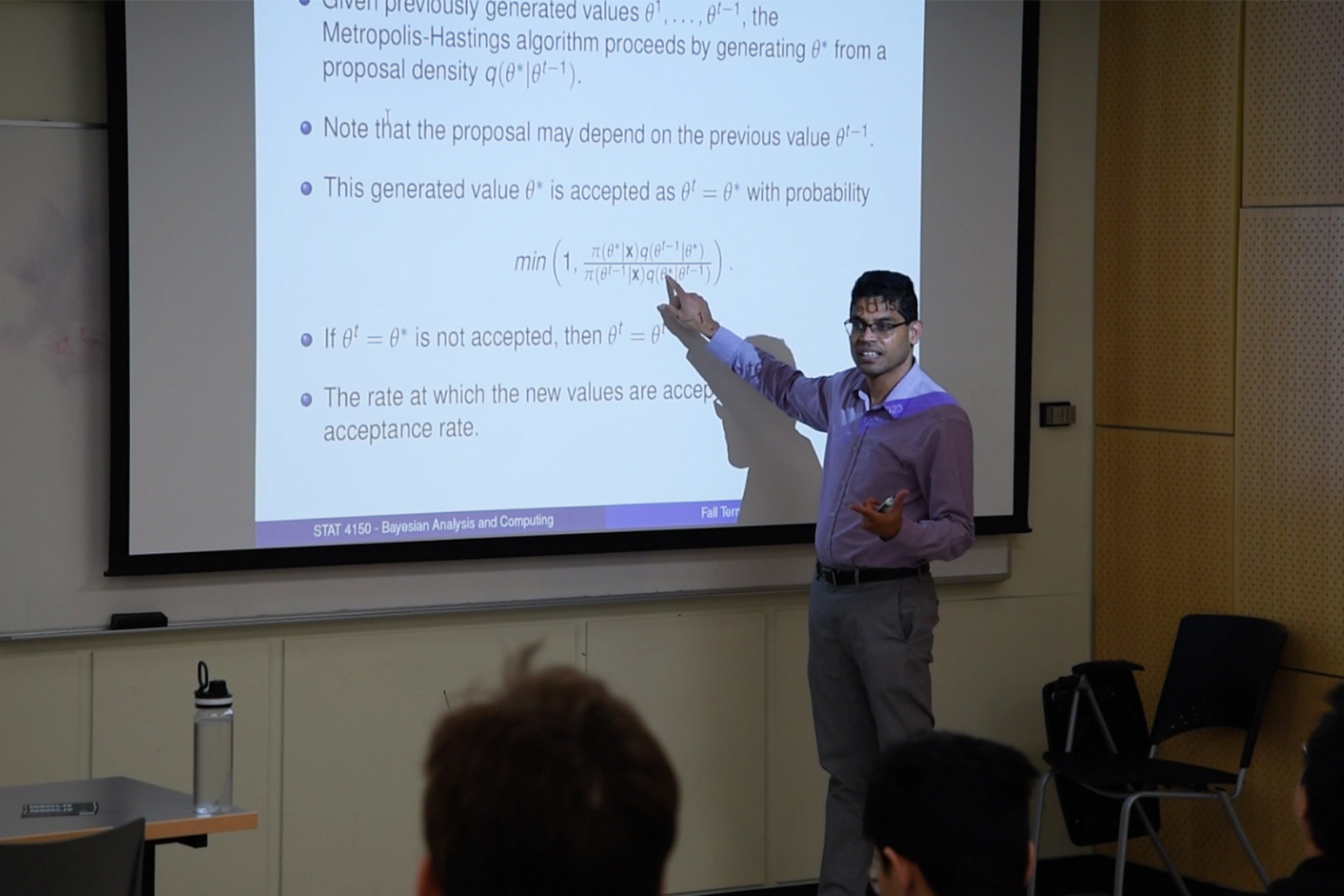 Saman Muthukumarana wearing a purple long sleeves teaching in a classroom.