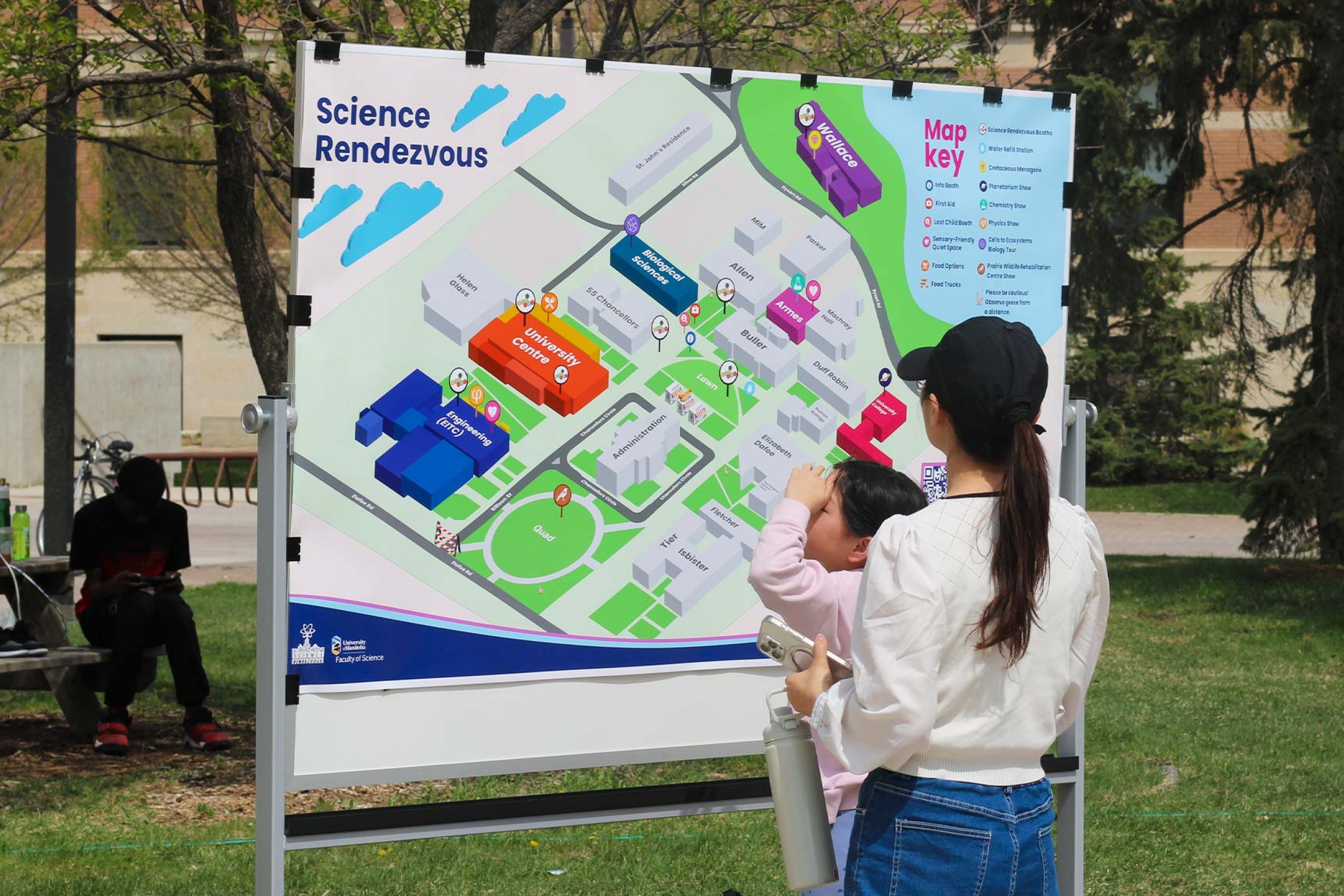 An attendee with a child looking at the Science Rendezvous 2025 physical map.