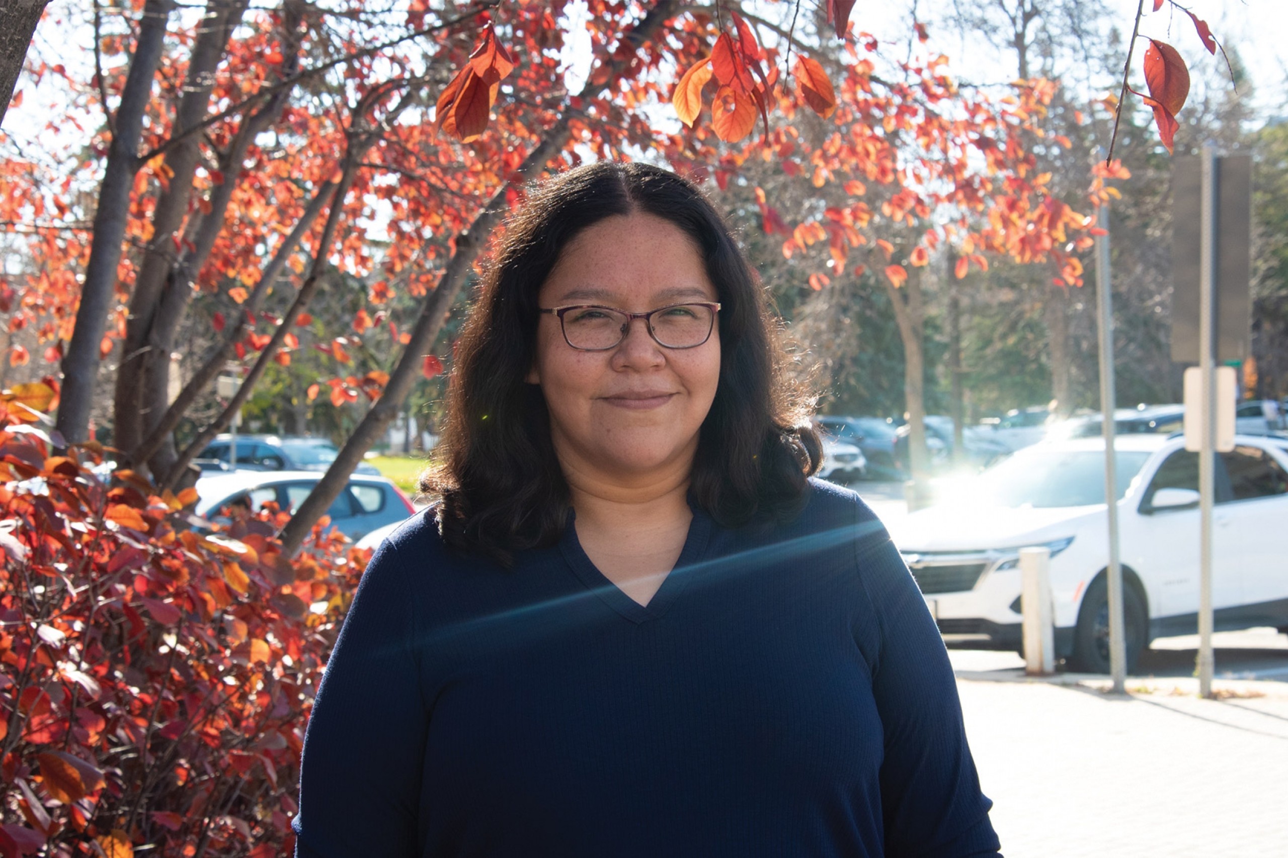 Shana wearing a blue long sleeves in front of a tree smiling at the camera.