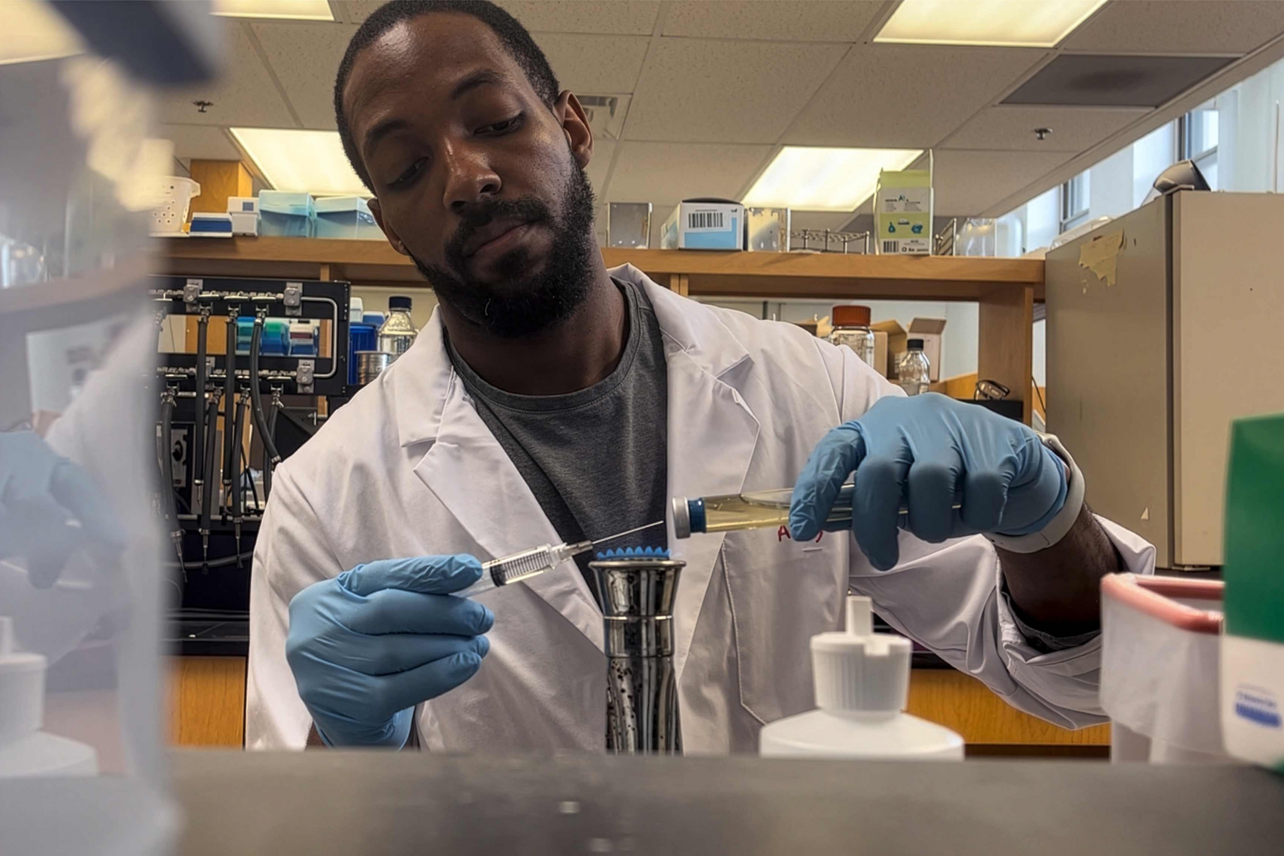 Steve Daley wearing a gloves and lab coat doing an experiment.
