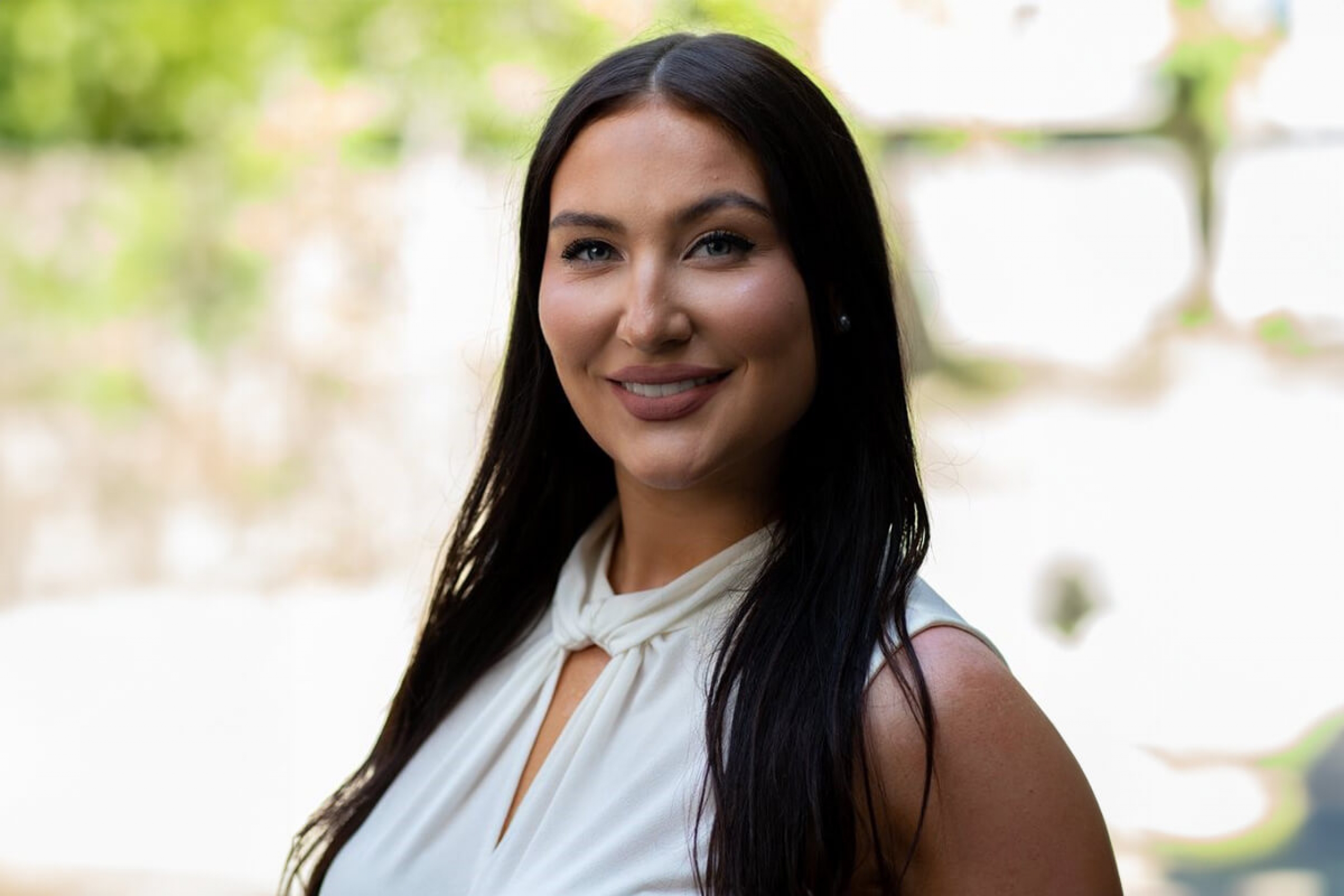 Sydney Levasseur-Puhach smiling at the camera. She has long, jet black hair and is wearing a white blouse.