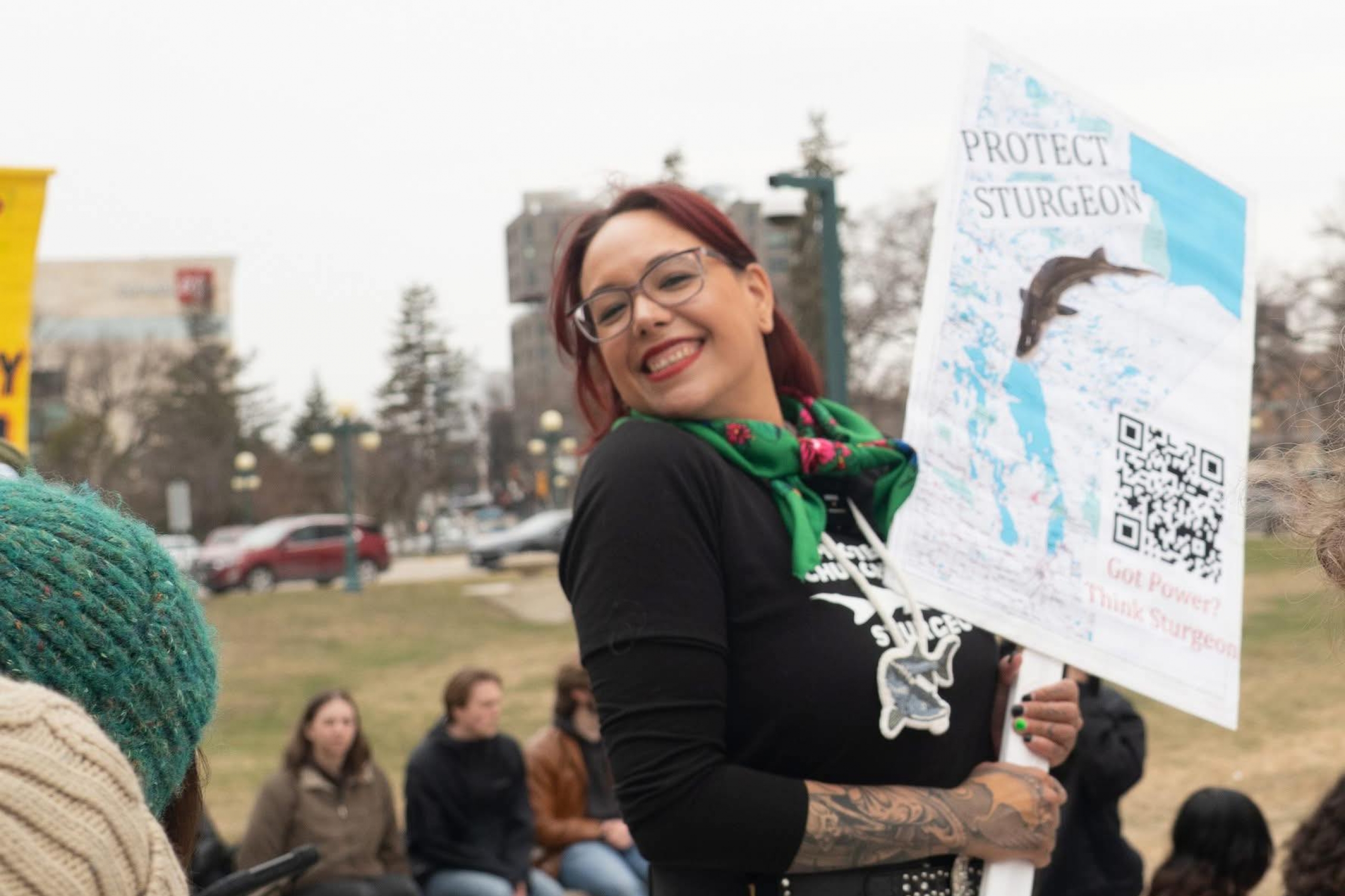 Female poses with a big smile while holding a sign that says "protect sturgeon".
