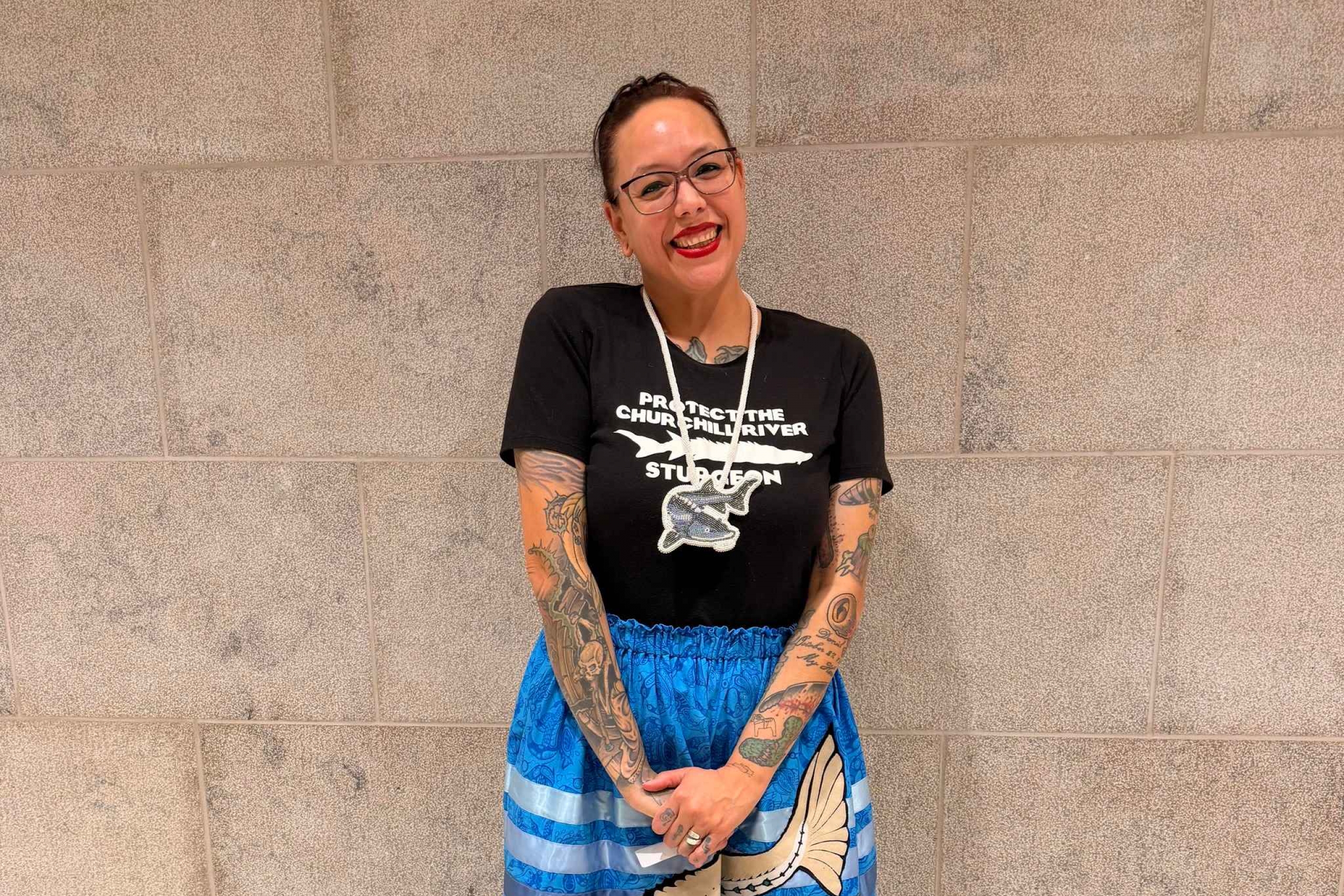 female smiling wearing blue ribbon skirt with sturgeon image sewn on.