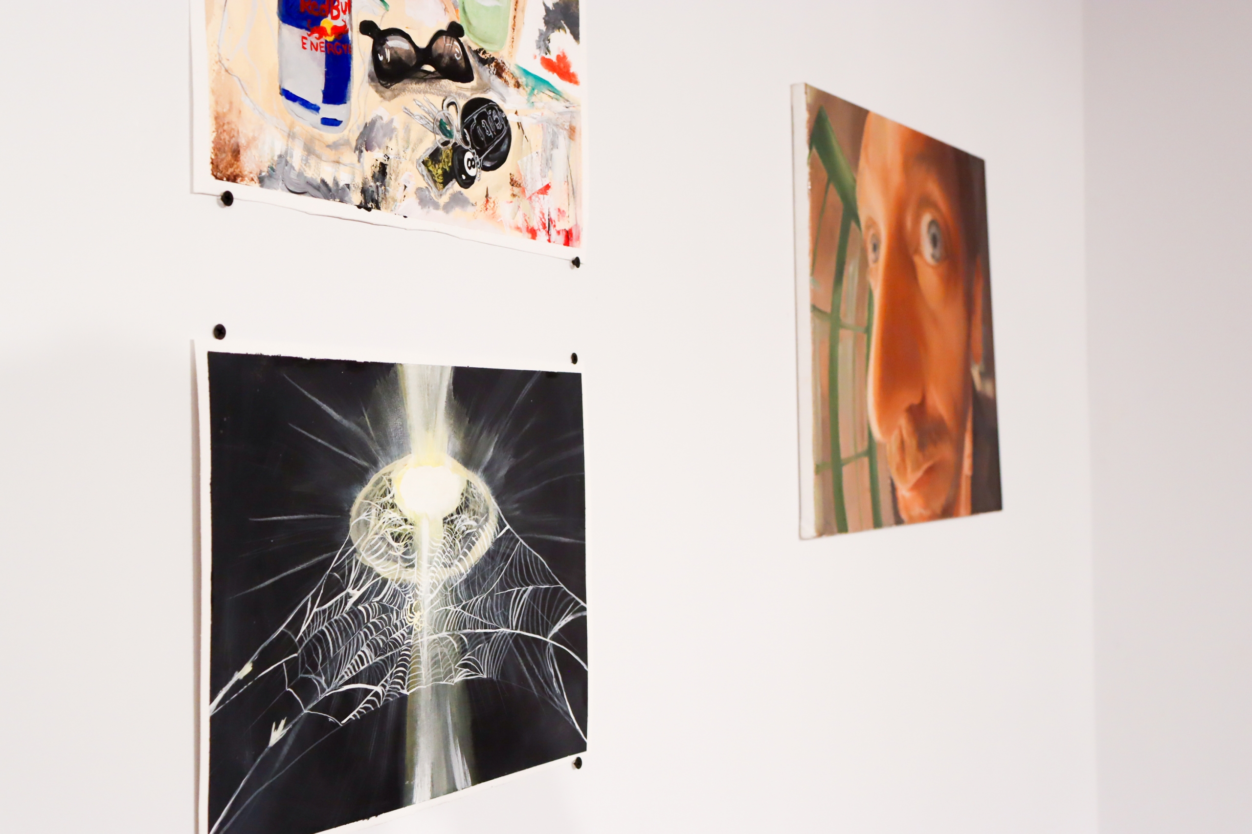 Detail of two works on paper — a still life and a spiderweb painting — alongside an oil self-portrait.
