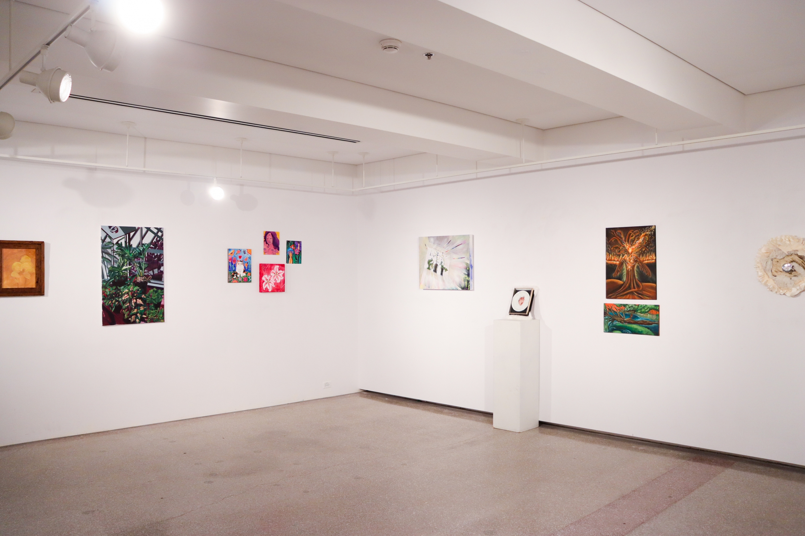 Wide installation view of the gallery's corner wall with paintings of varying scale hung in a salon-style arrangement.