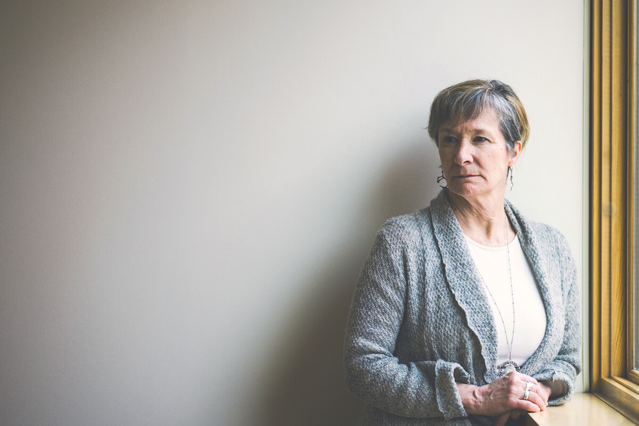 Josee Lavoie standing near a wall, looking away from the light of the window.