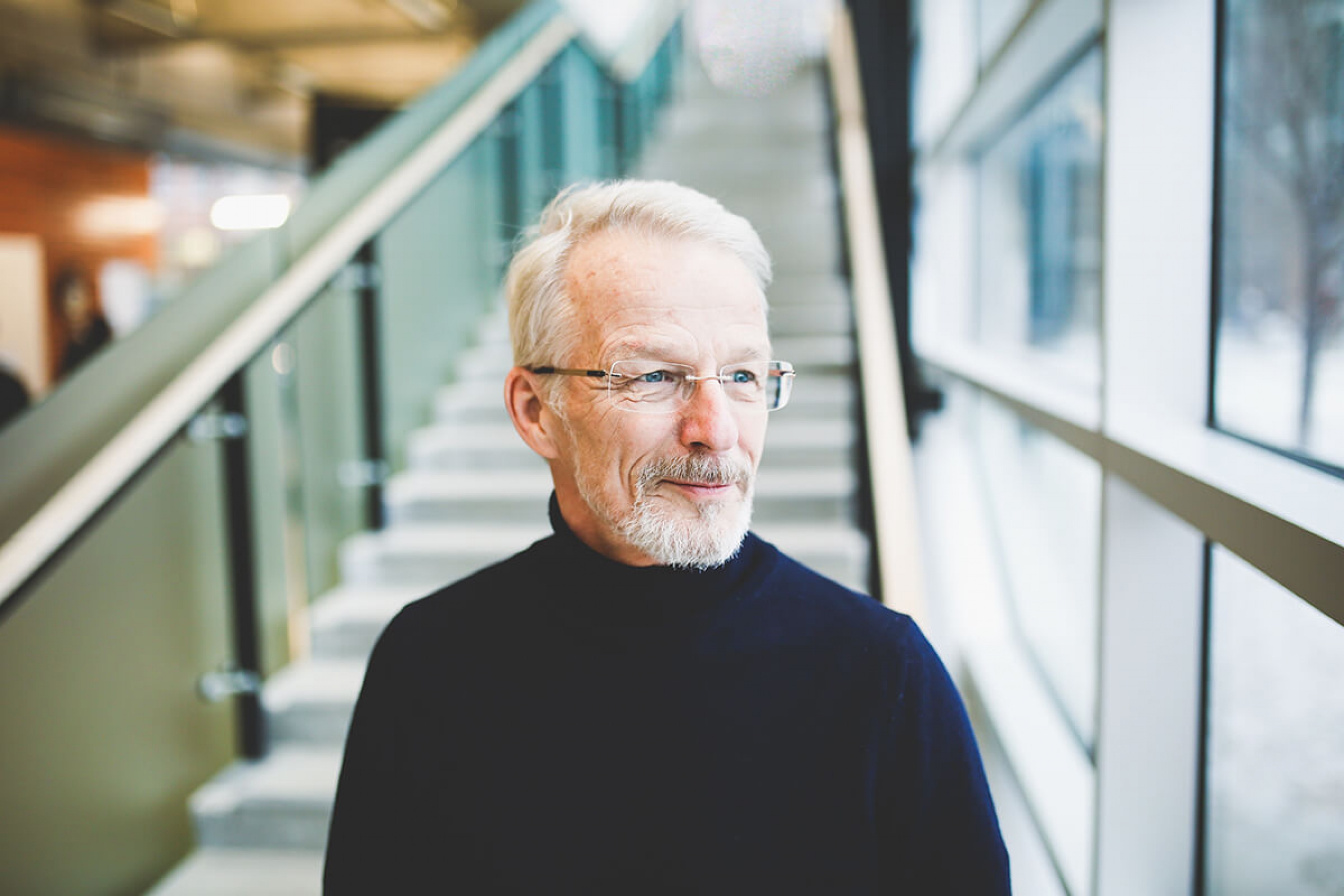 Ties Boerma stands at the based of a staircase, looking out the window.